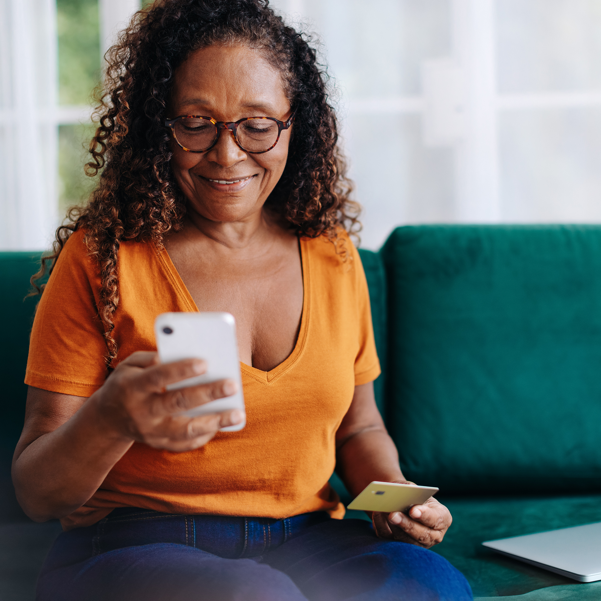 A woman is sitting on a couch looking at her phone.