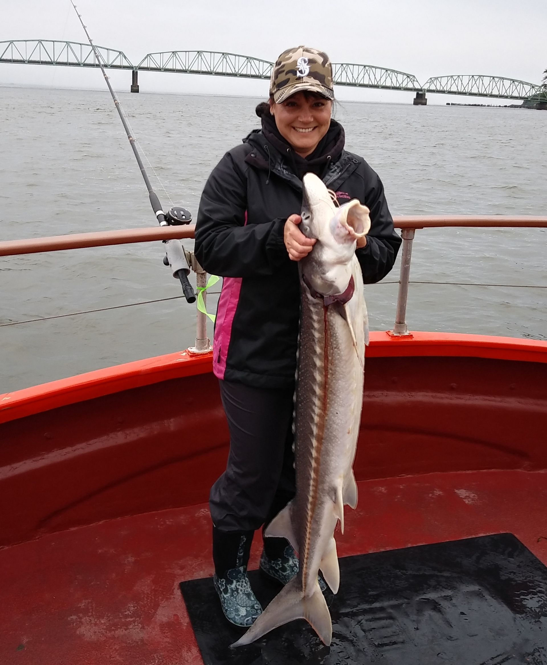 A woman is holding a large fish on a boat