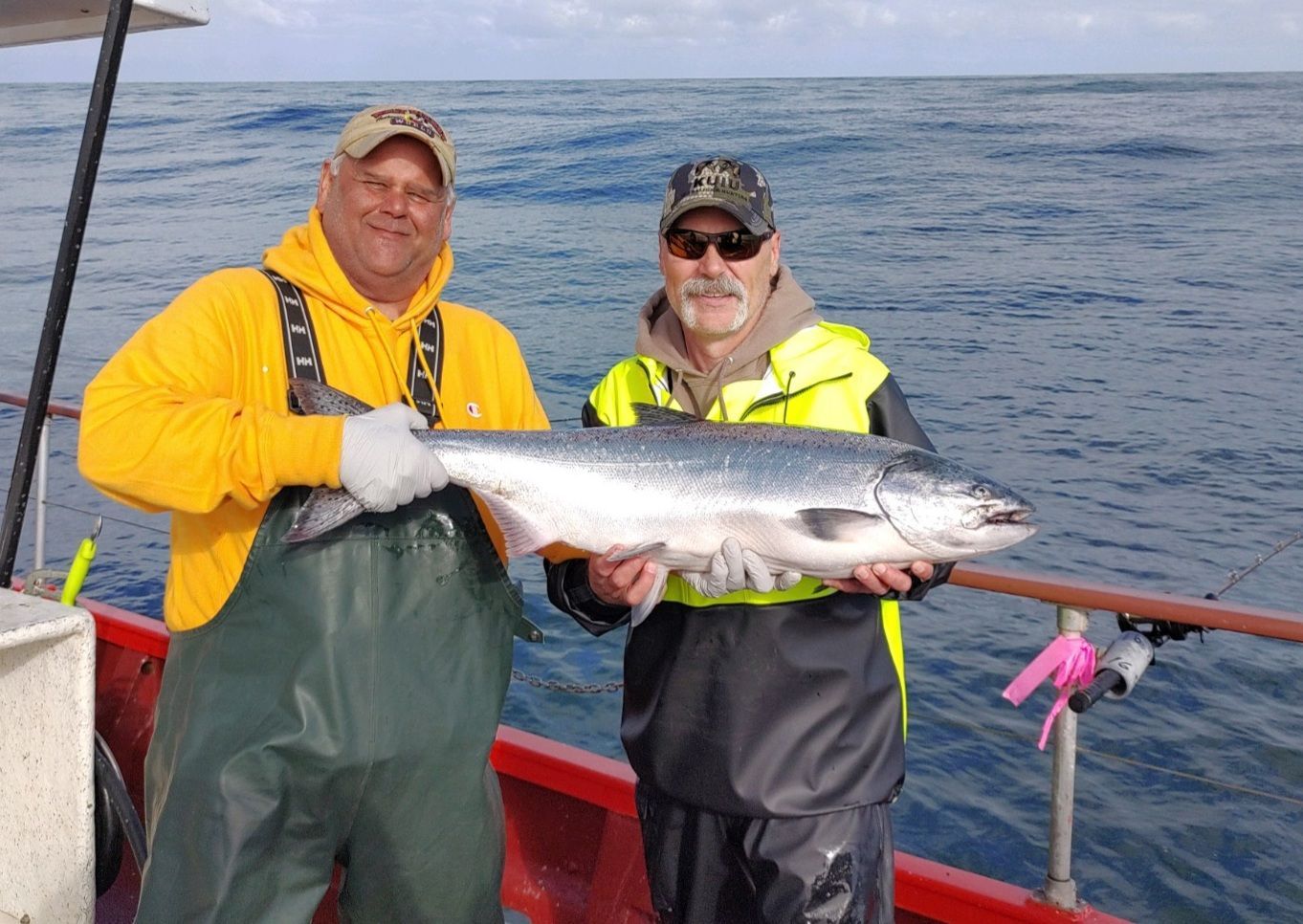 Two men are holding a large fish on a boat in the ocean.