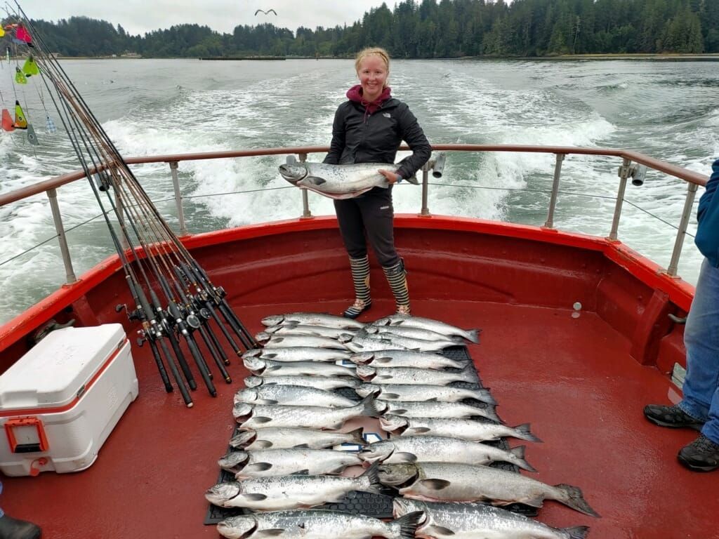 A woman is standing on a boat holding a large fish.