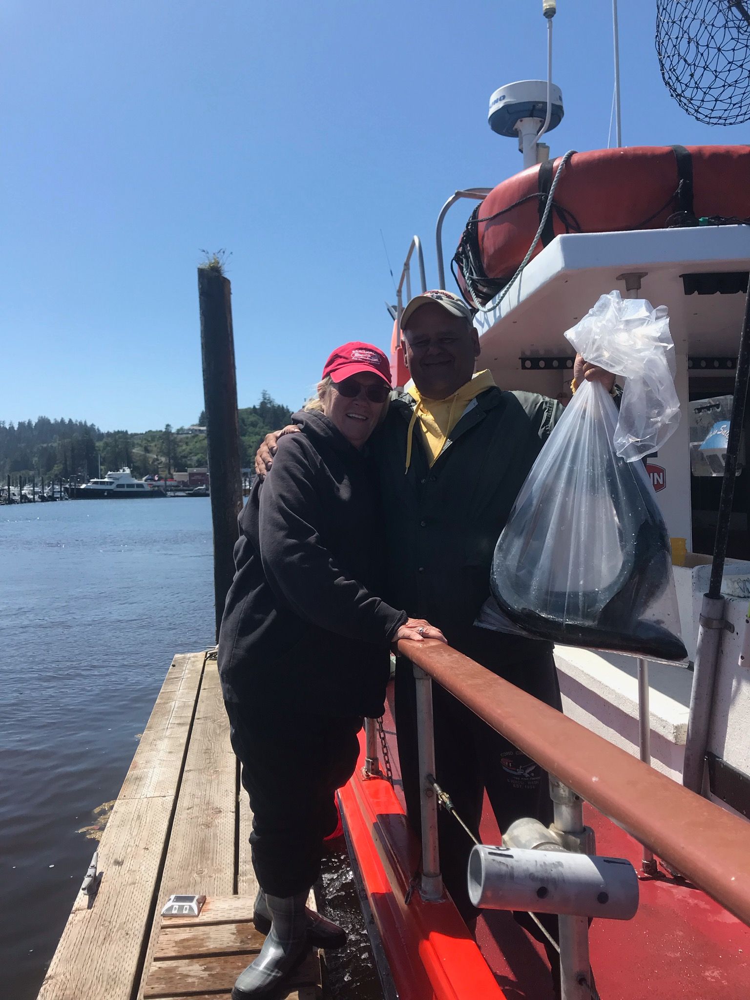 A man and a woman are standing on a dock next to a boat.