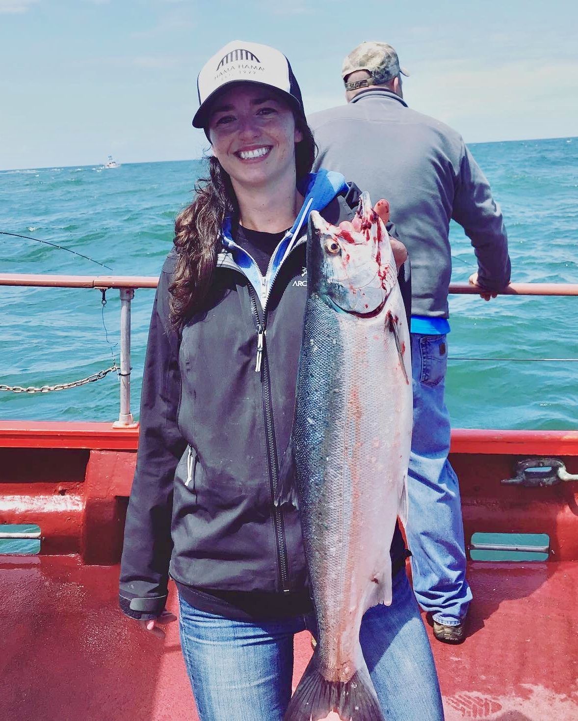 A woman is holding a large fish on a boat
