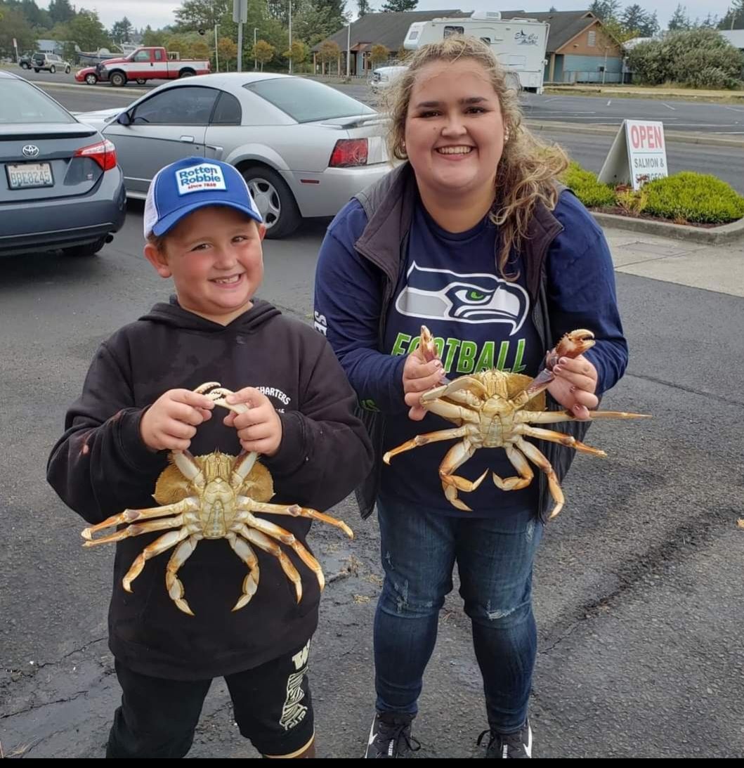 A woman and a boy holding crabs in a parking lot