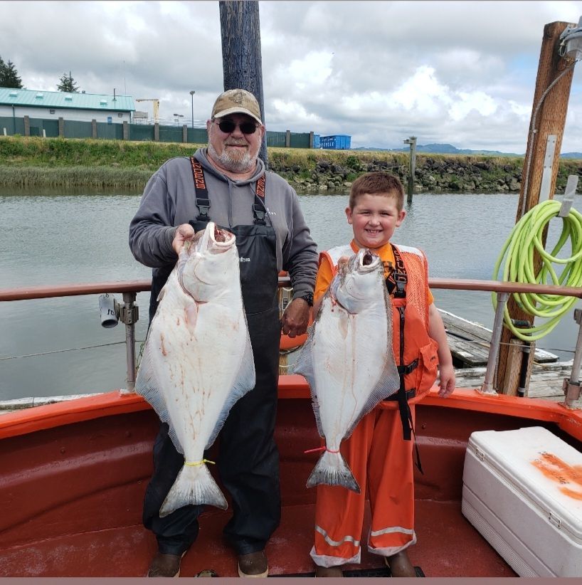 A man and a boy standing on a boat holding fish