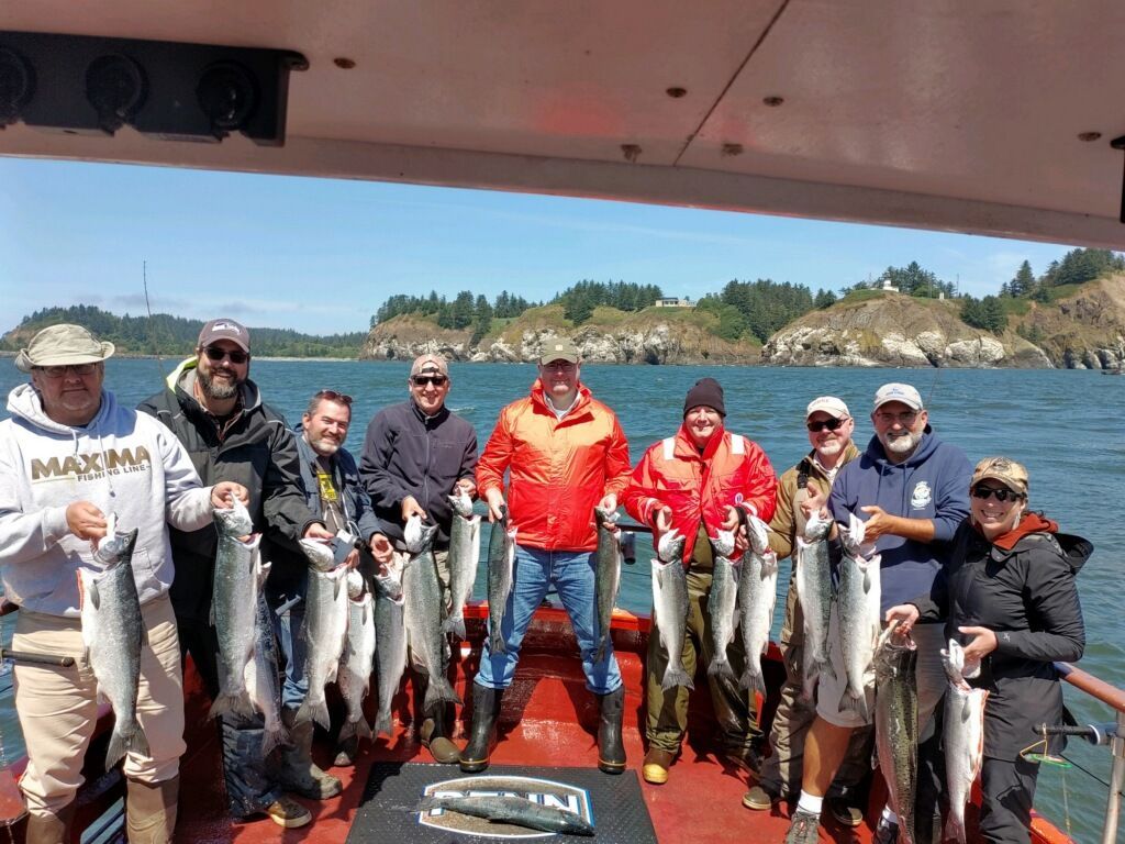 A group of people are standing on a boat holding fish.
