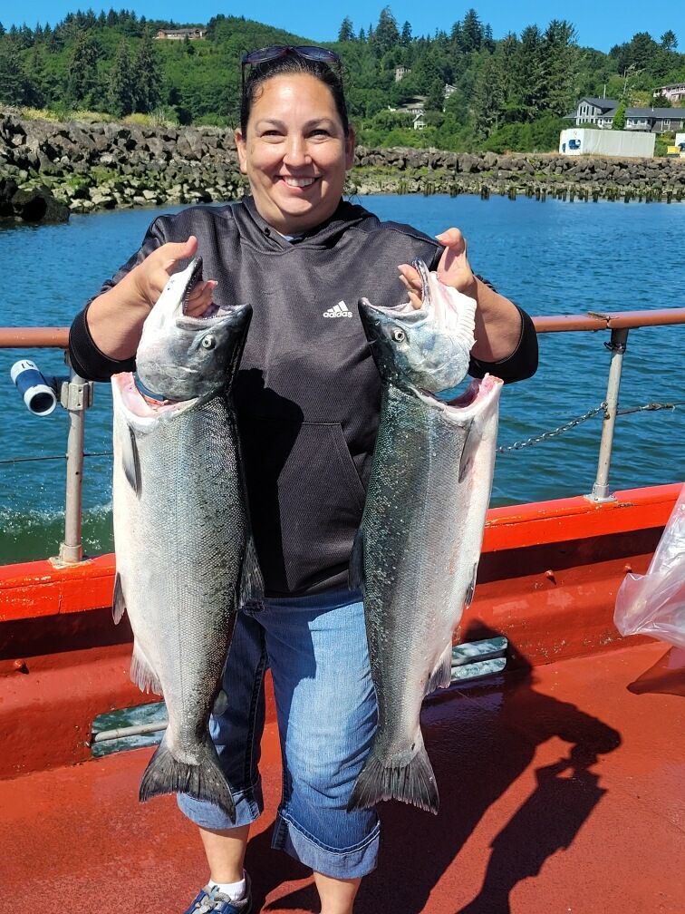 A woman is holding two large fish on a boat