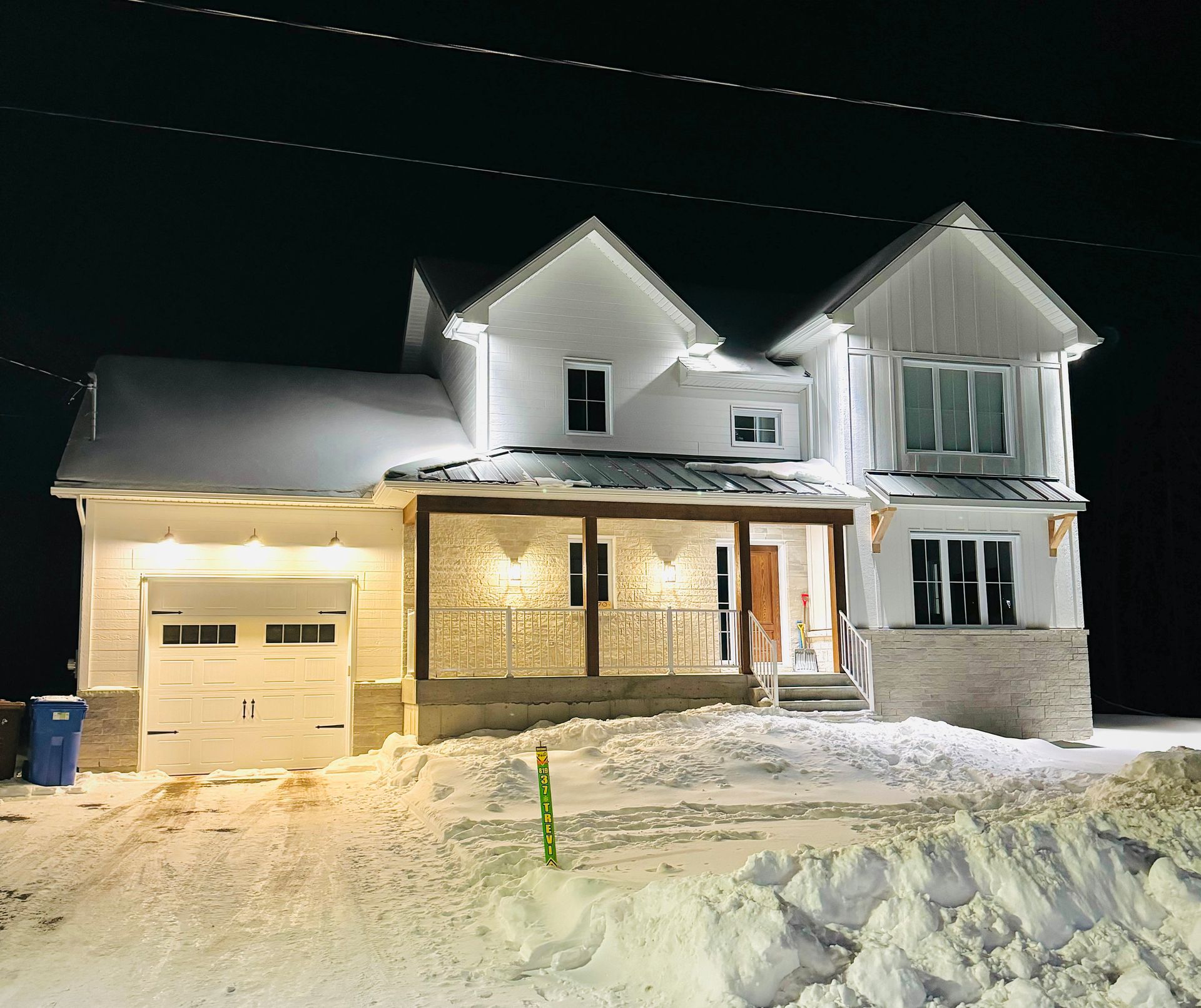 Une grande maison blanche est couverte de neige la nuit
