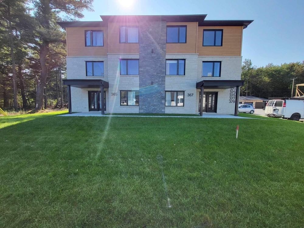 Une grande maison avec de nombreuses fenêtres est située au sommet d'une pelouse verdoyante.