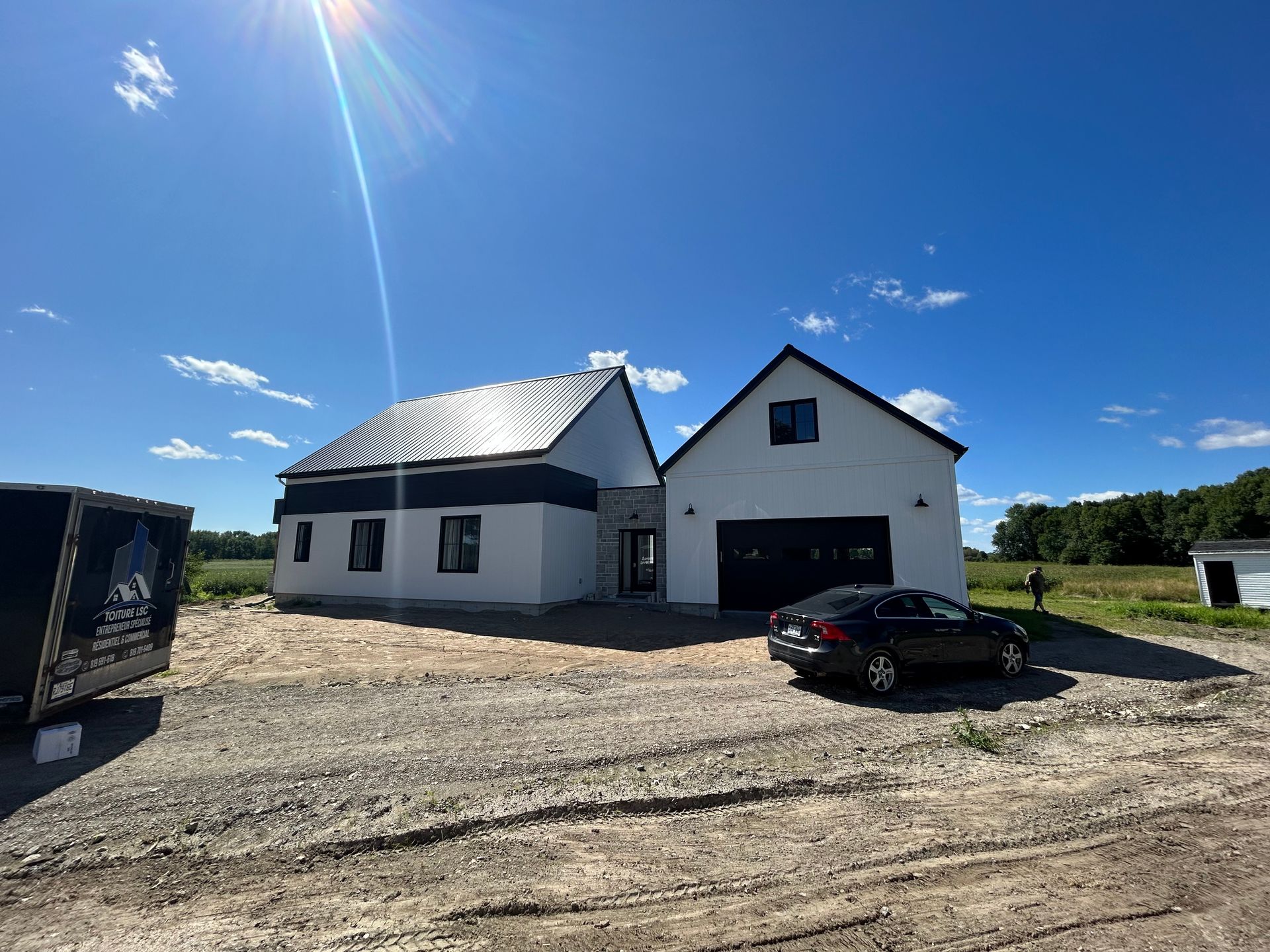 Une maison blanche avec une voiture noire garée devant.