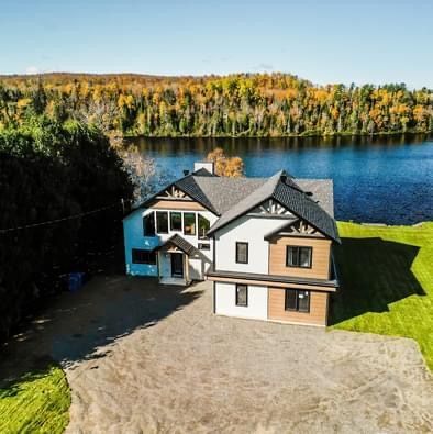 Une vue aérienne d'une maison au bord d'un lac entouré d'arbres.