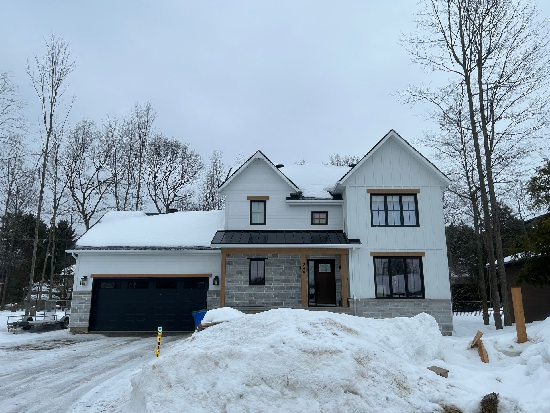 Une grande maison blanche avec un garage est recouverte de neige.