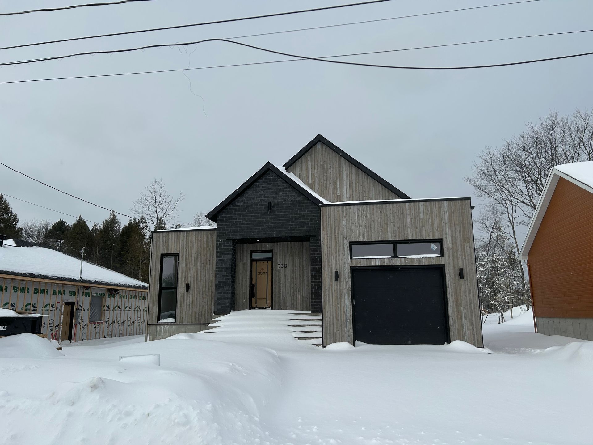 Une maison avec garage est recouverte de neige.
