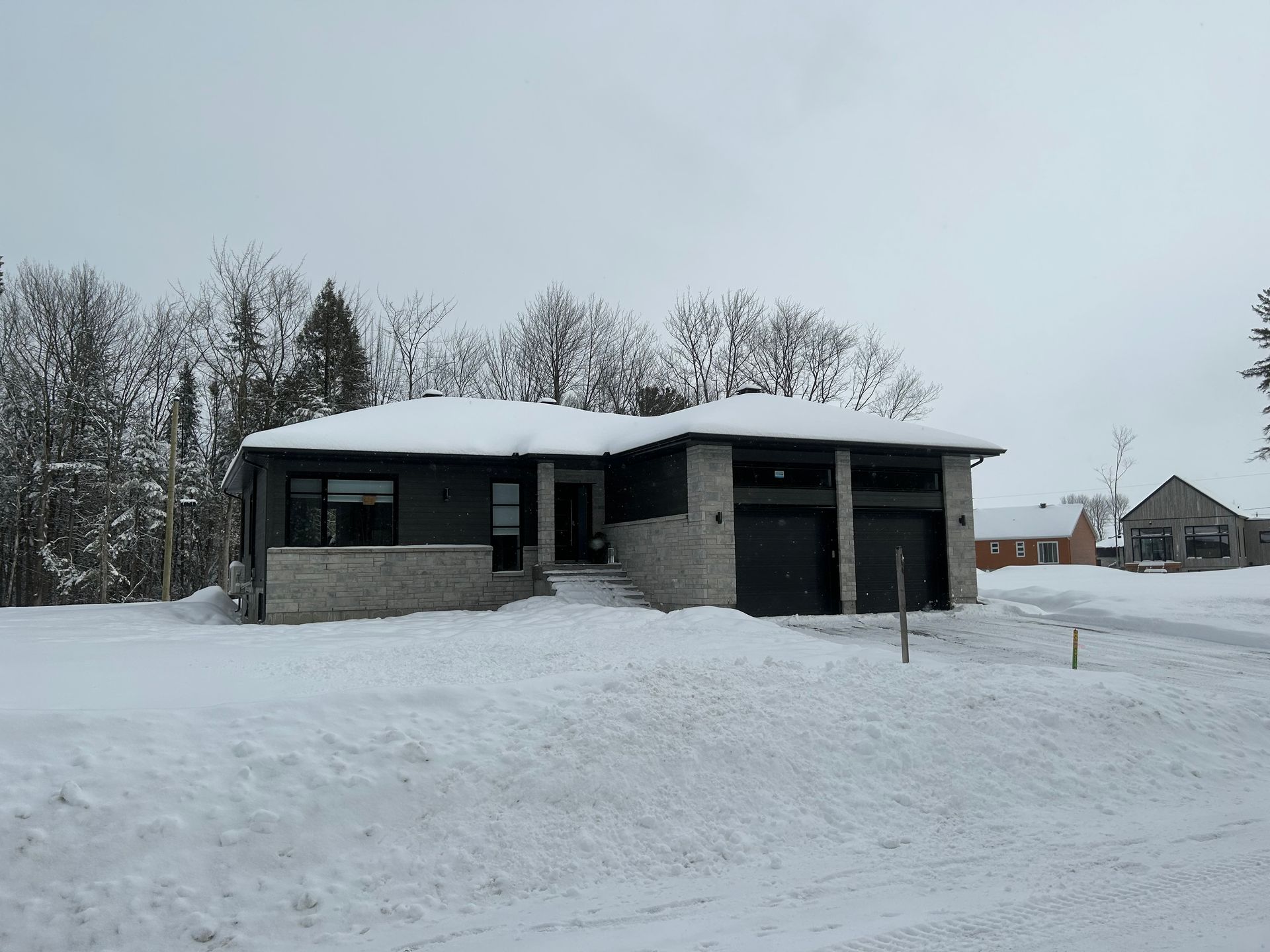 Une maison avec garage est recouverte de neige.