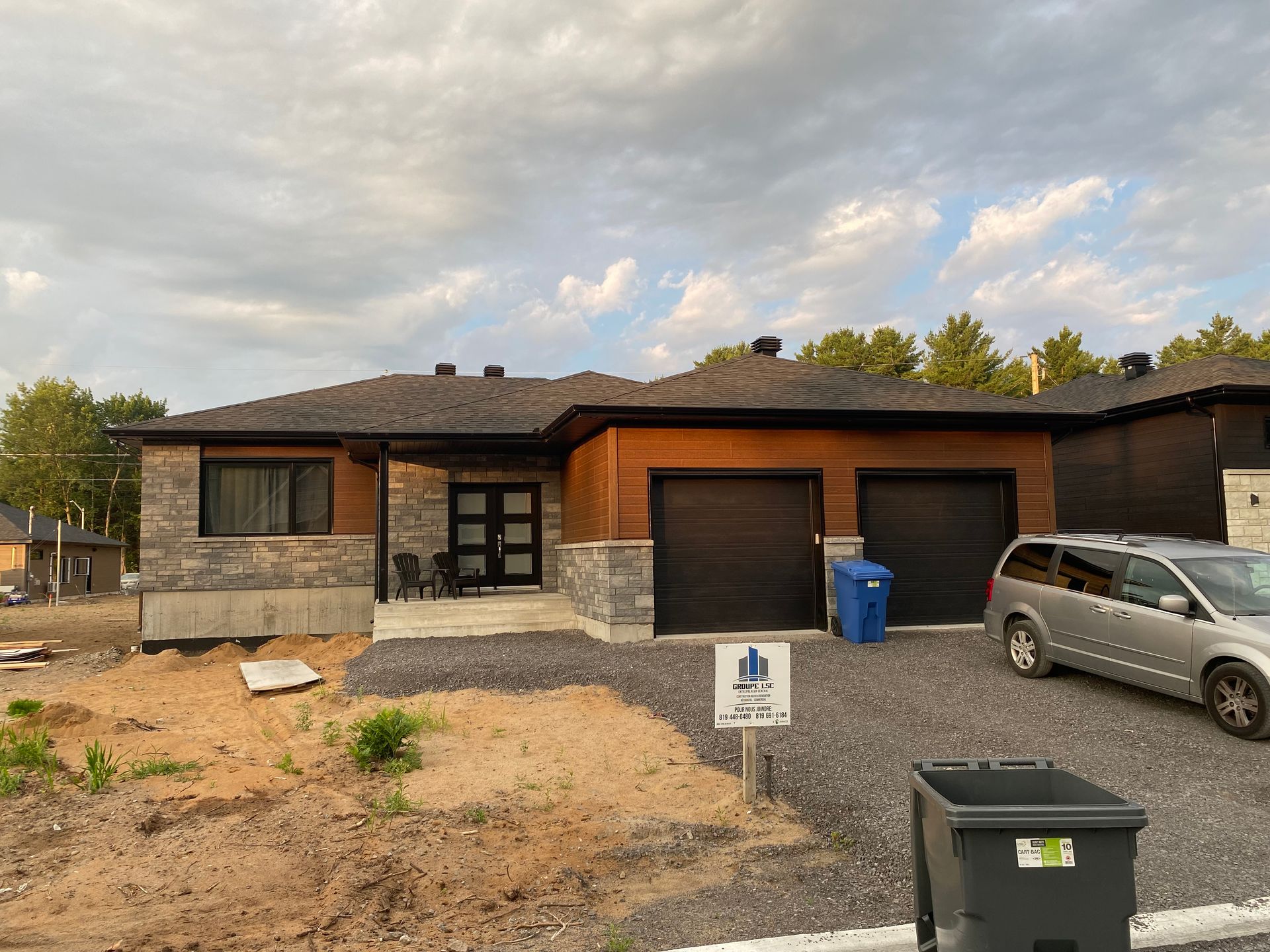 Une voiture est garée devant une maison en construction.