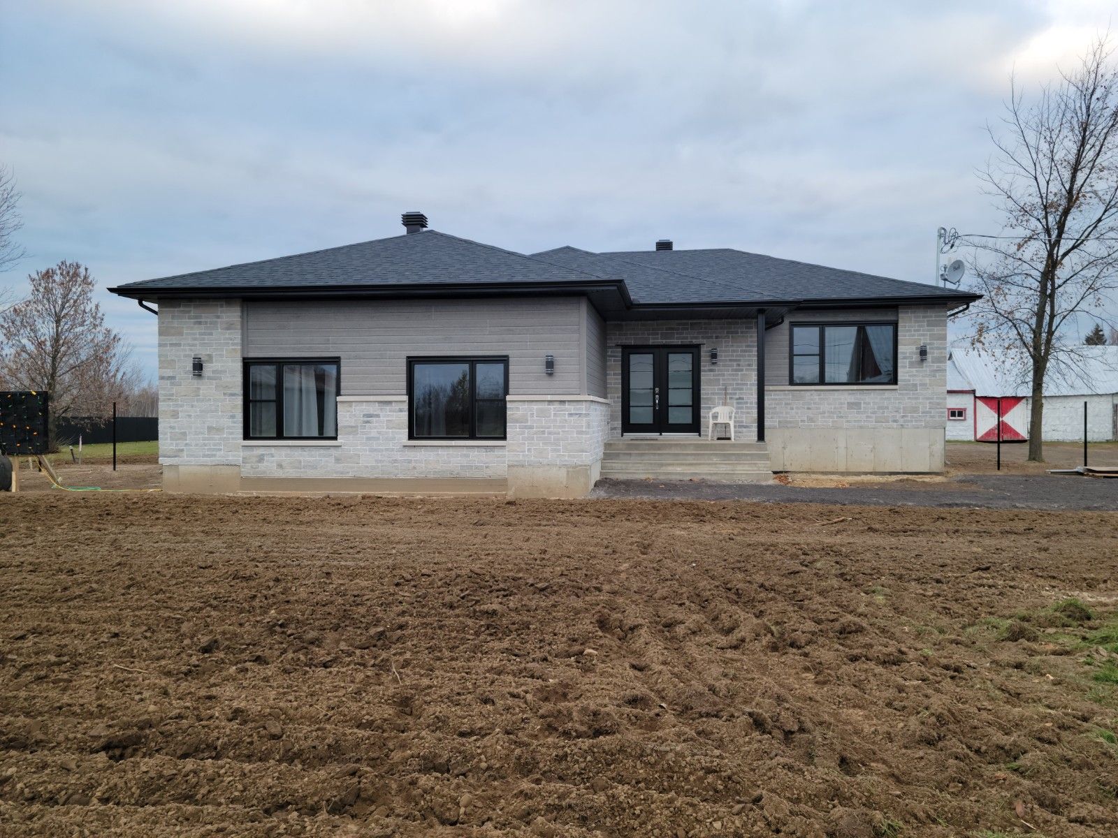 Une maison est située au milieu d'un champ de terre.