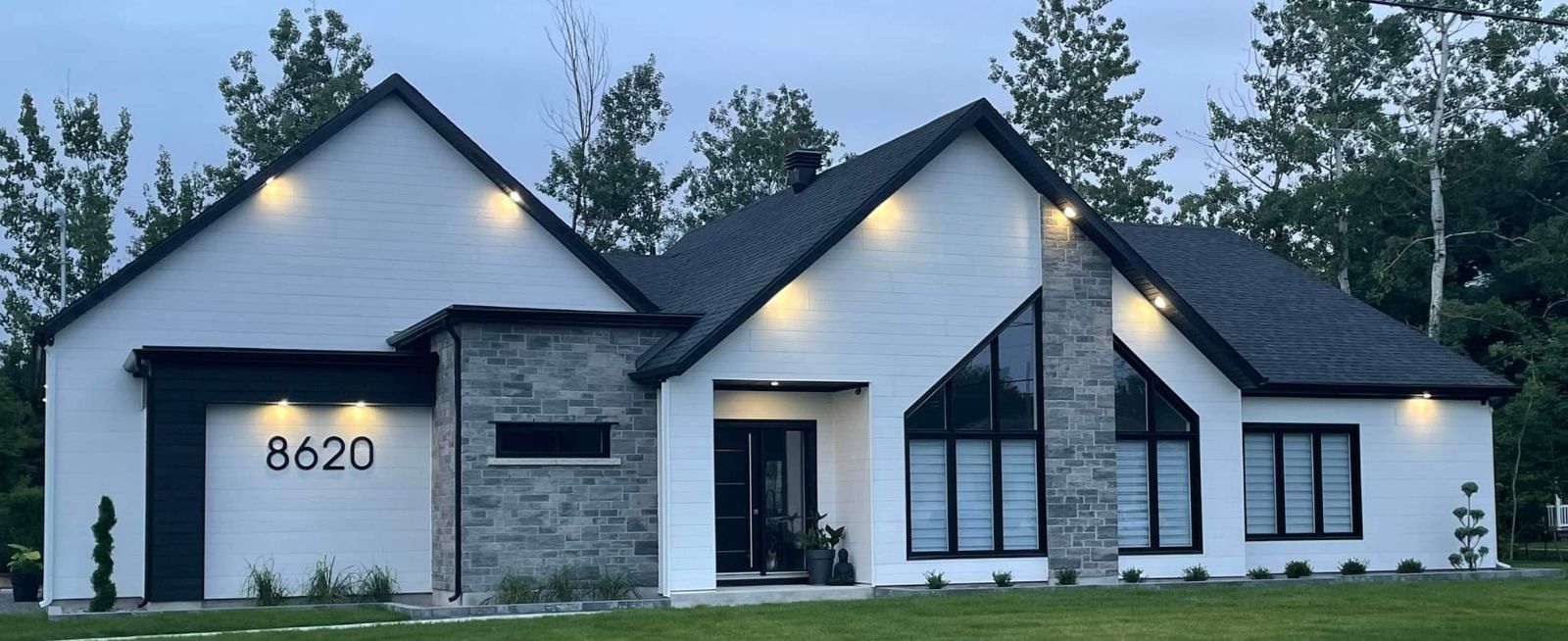 Une maison blanche avec un toit noir et le numéro 8620 sur la façade