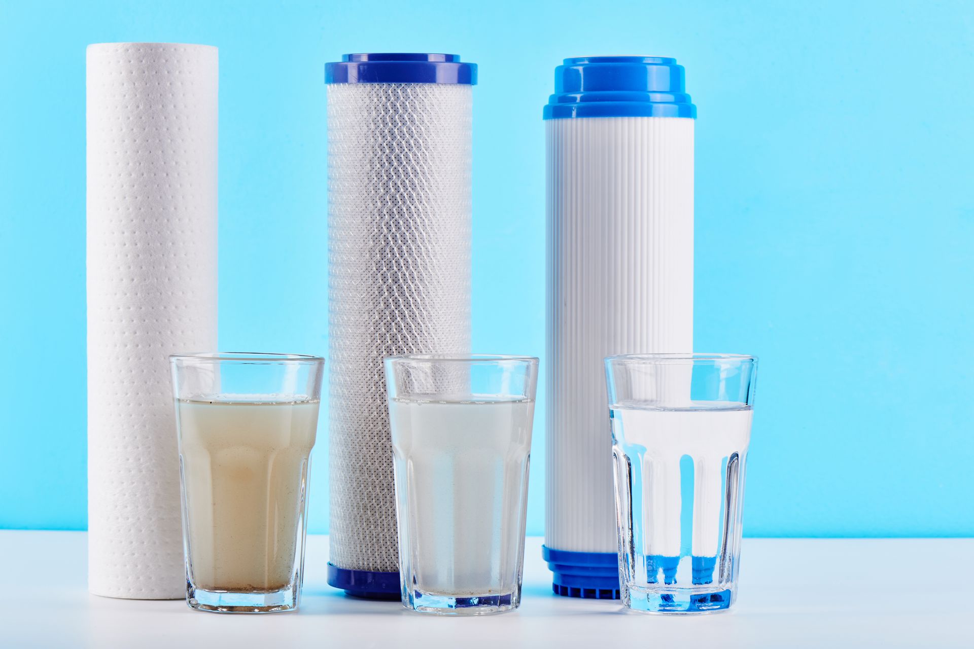 Three glasses of water and three filters on a table.