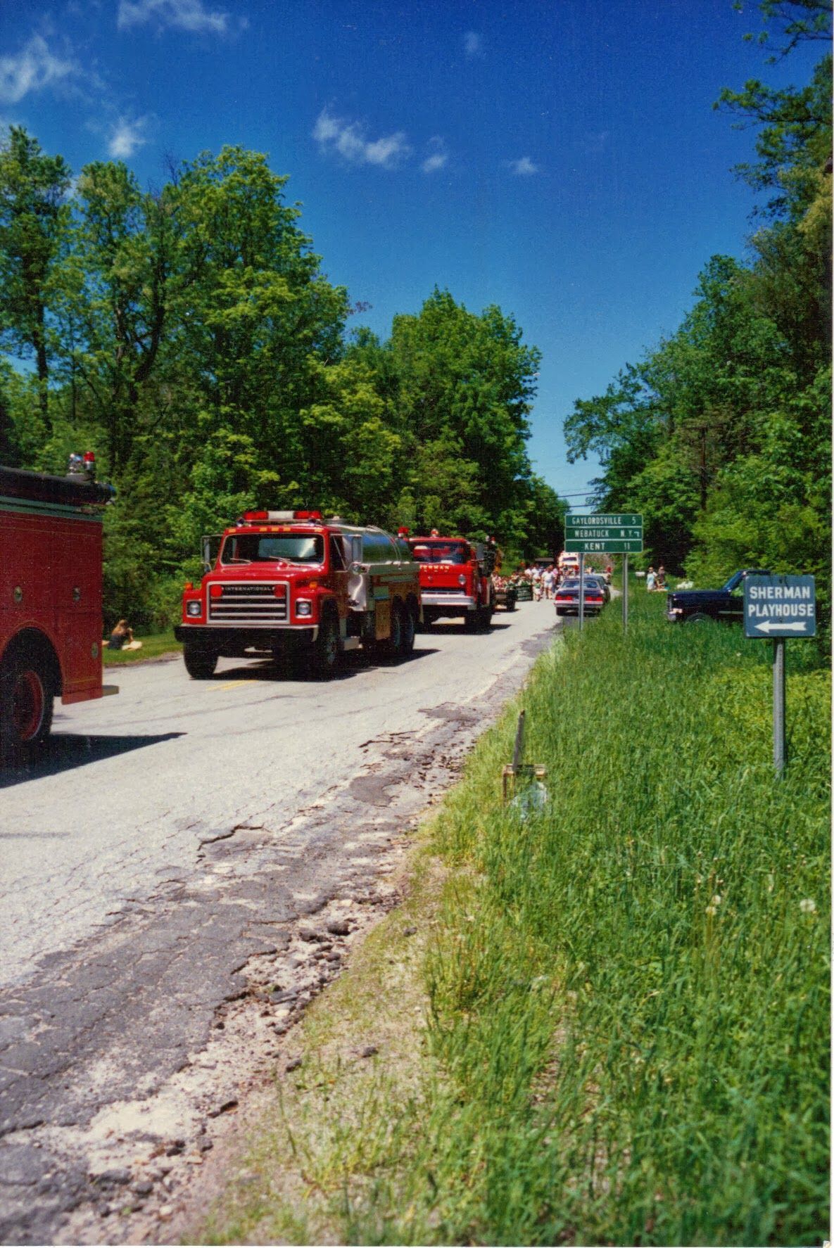 A row of red fire trucks are parked on the side of a road.