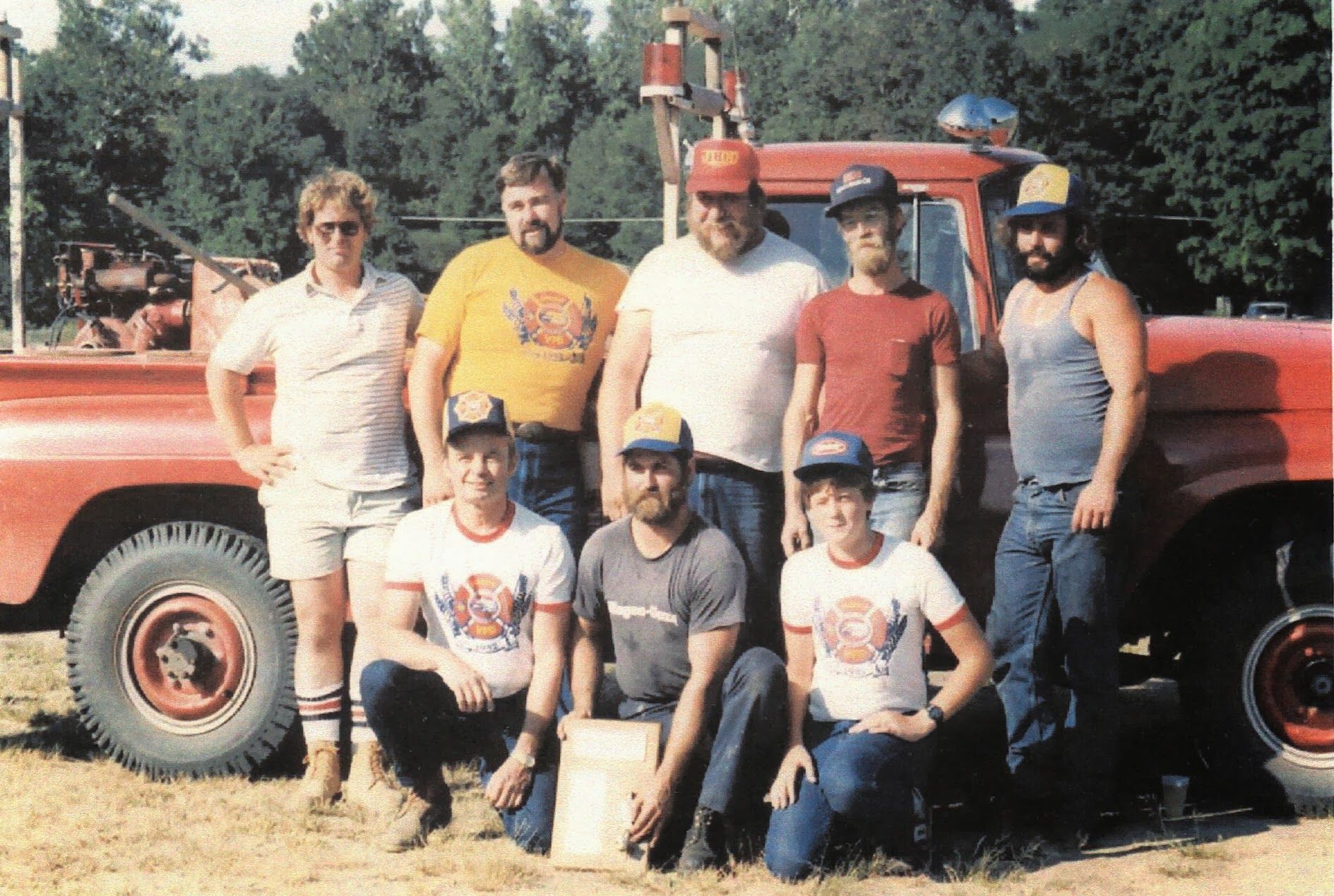 A group of men are posing for a picture in front of a red truck