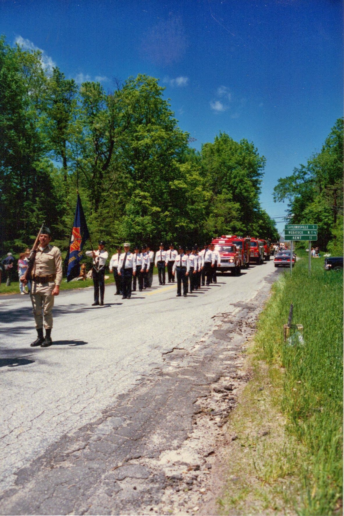 A group of people marching down a road with trees in the background