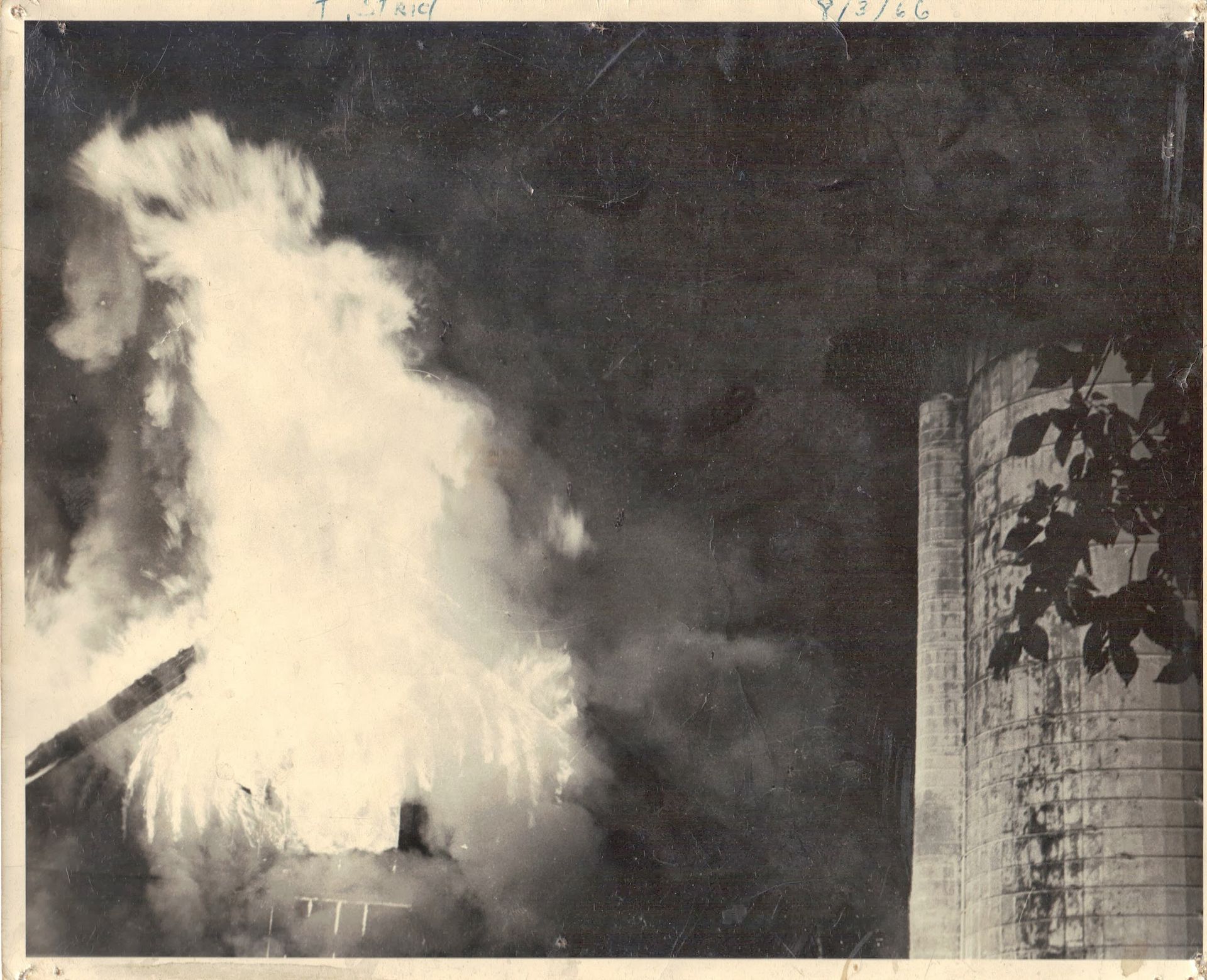 A black and white photo of a fire coming out of a building