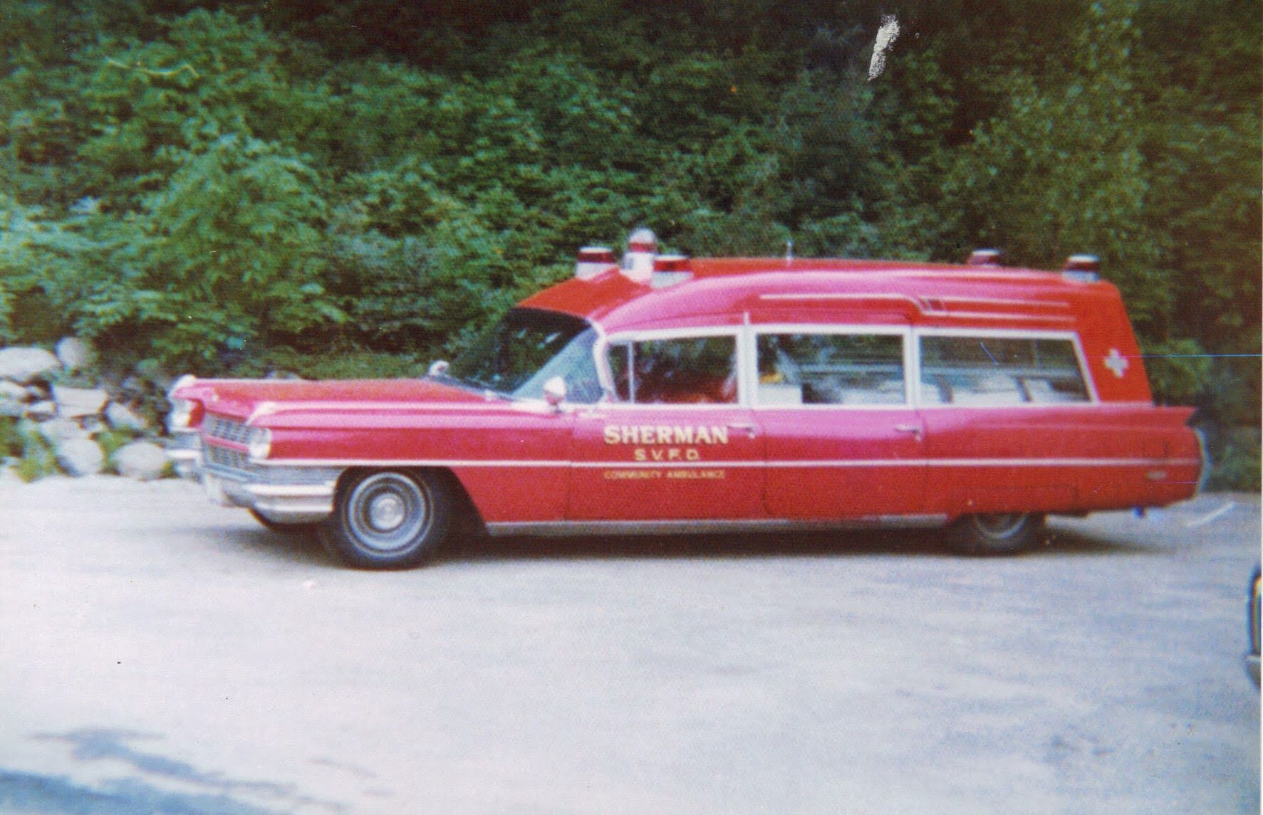 A red ambulance is parked in a parking lot.