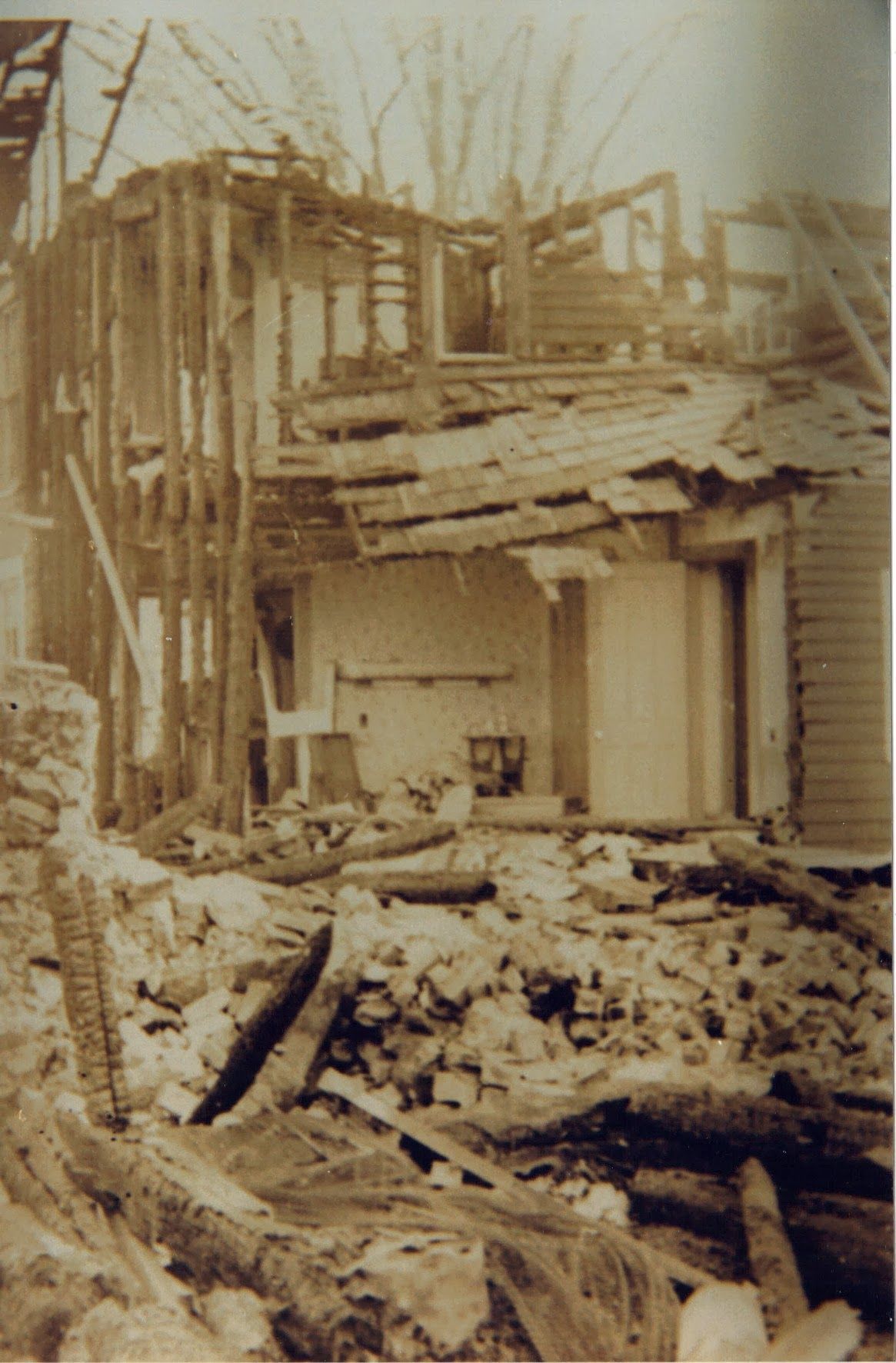 A black and white photo of a house being demolished