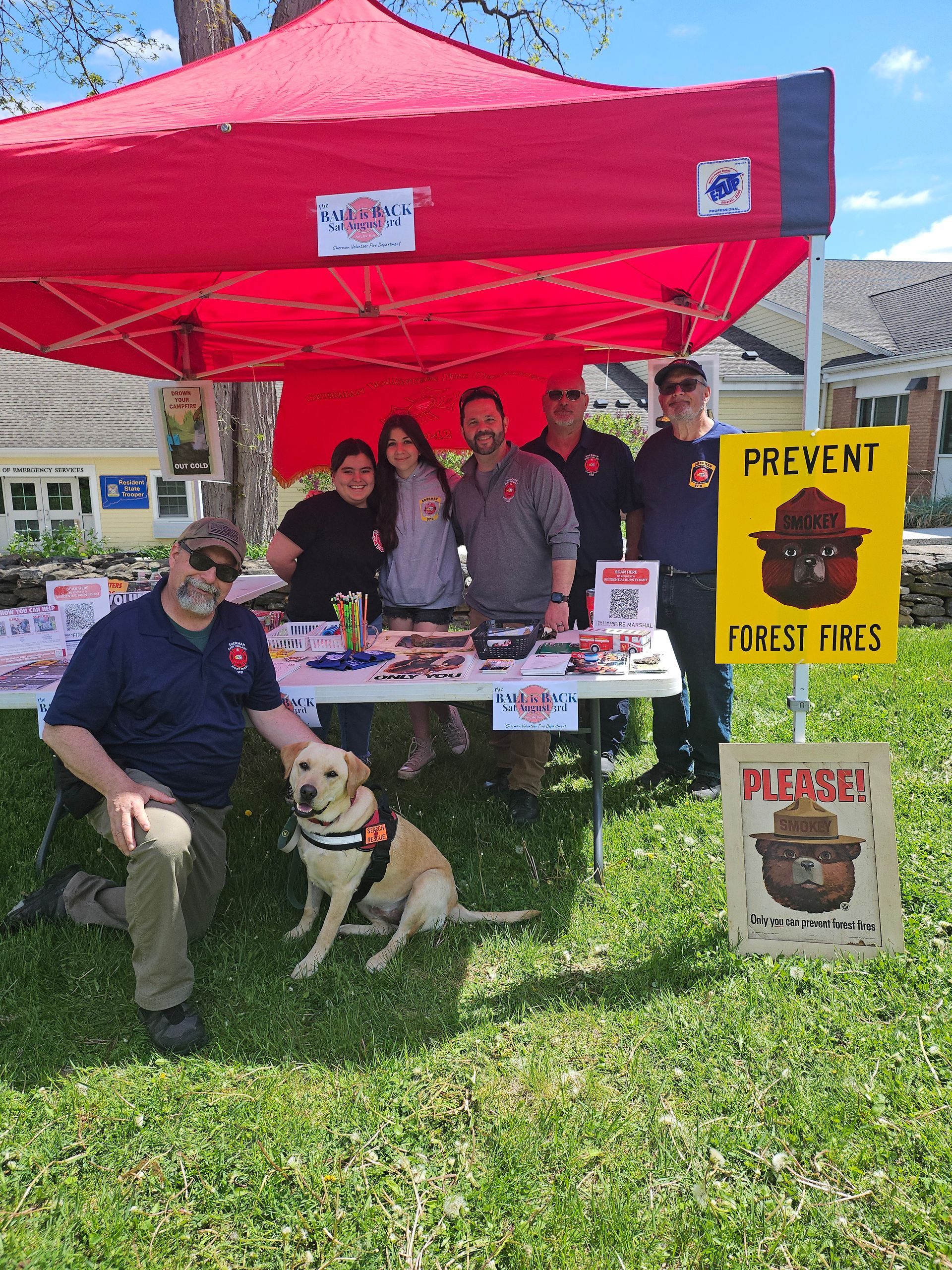 A group of people standing around a table with a dog.