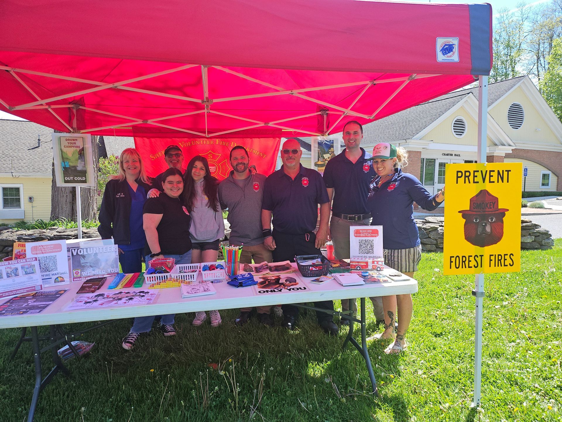 A group of people standing around a table under a red tent.