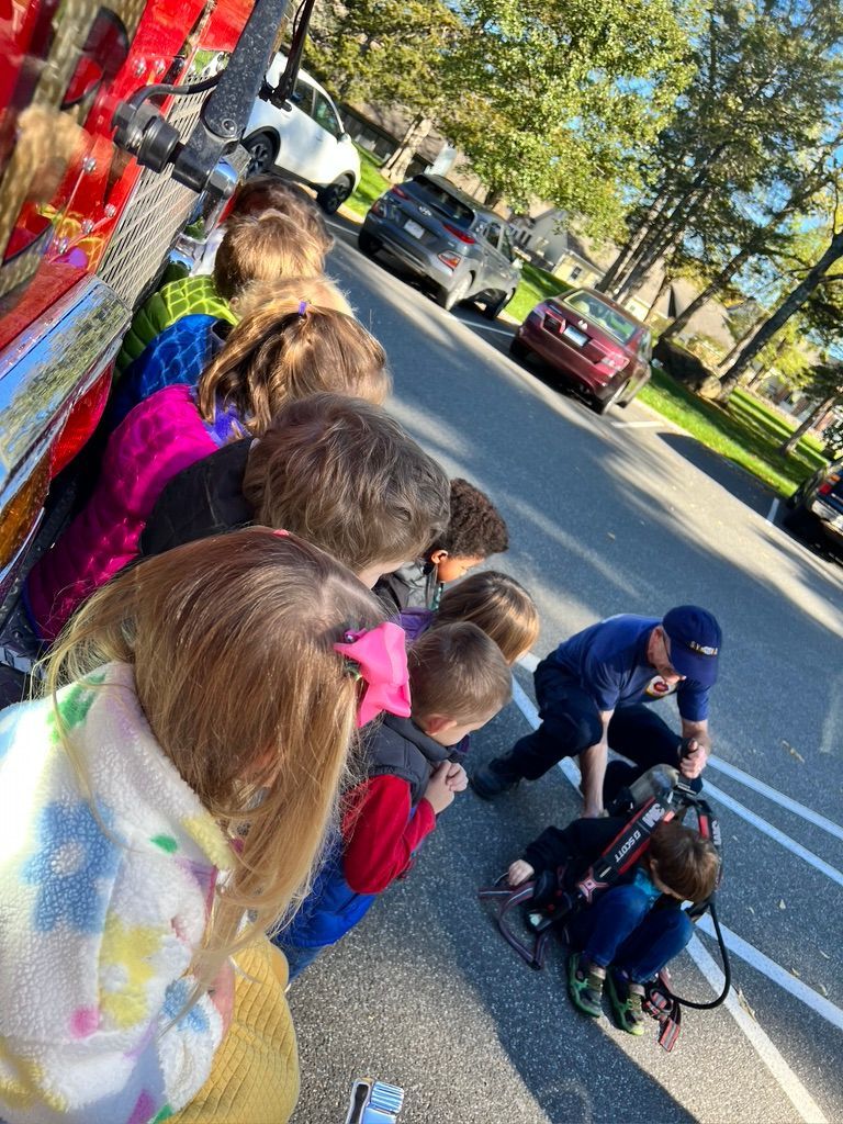 A group of children are standing in a line on the side of the road.