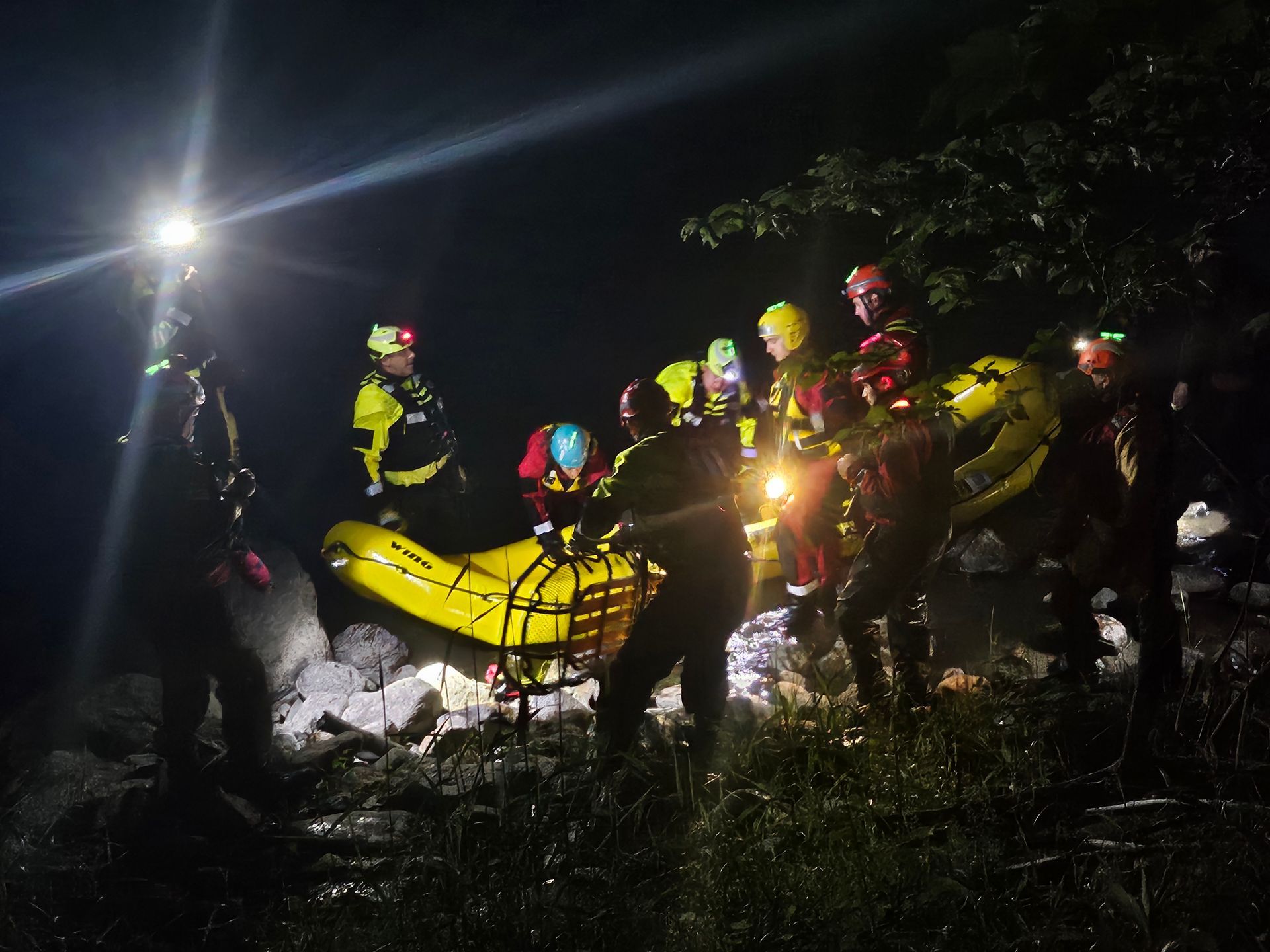 A group of people are standing around a yellow raft at night.
