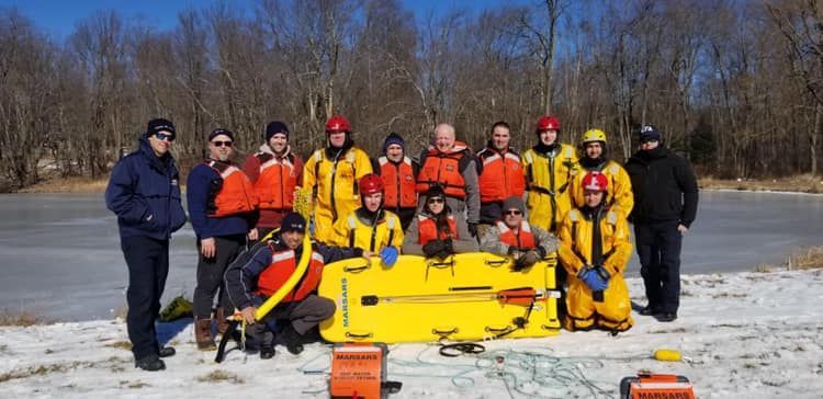 A group of people standing next to a yellow stretcher in the snow.