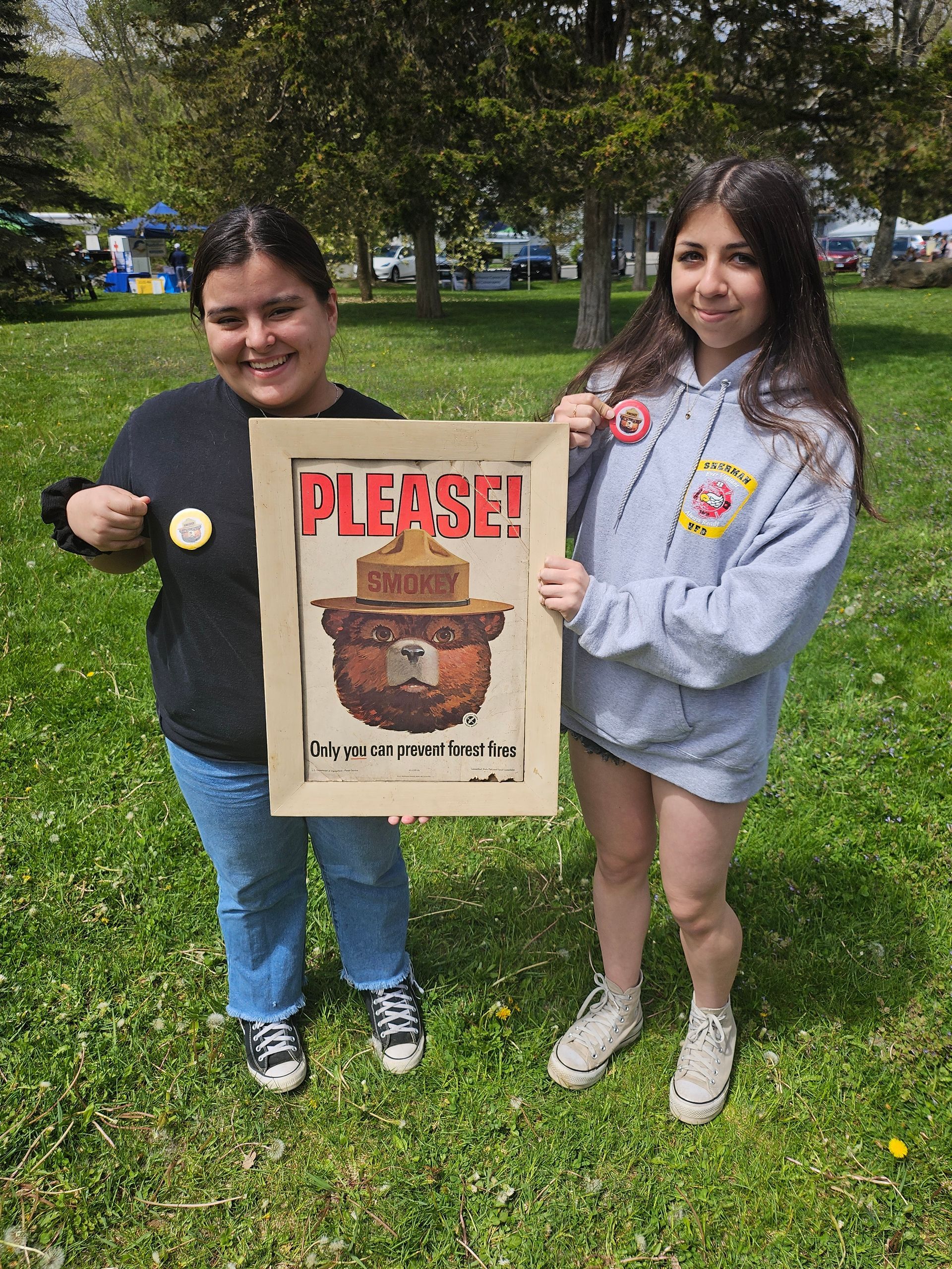 Two women are holding a sign that says please on it.