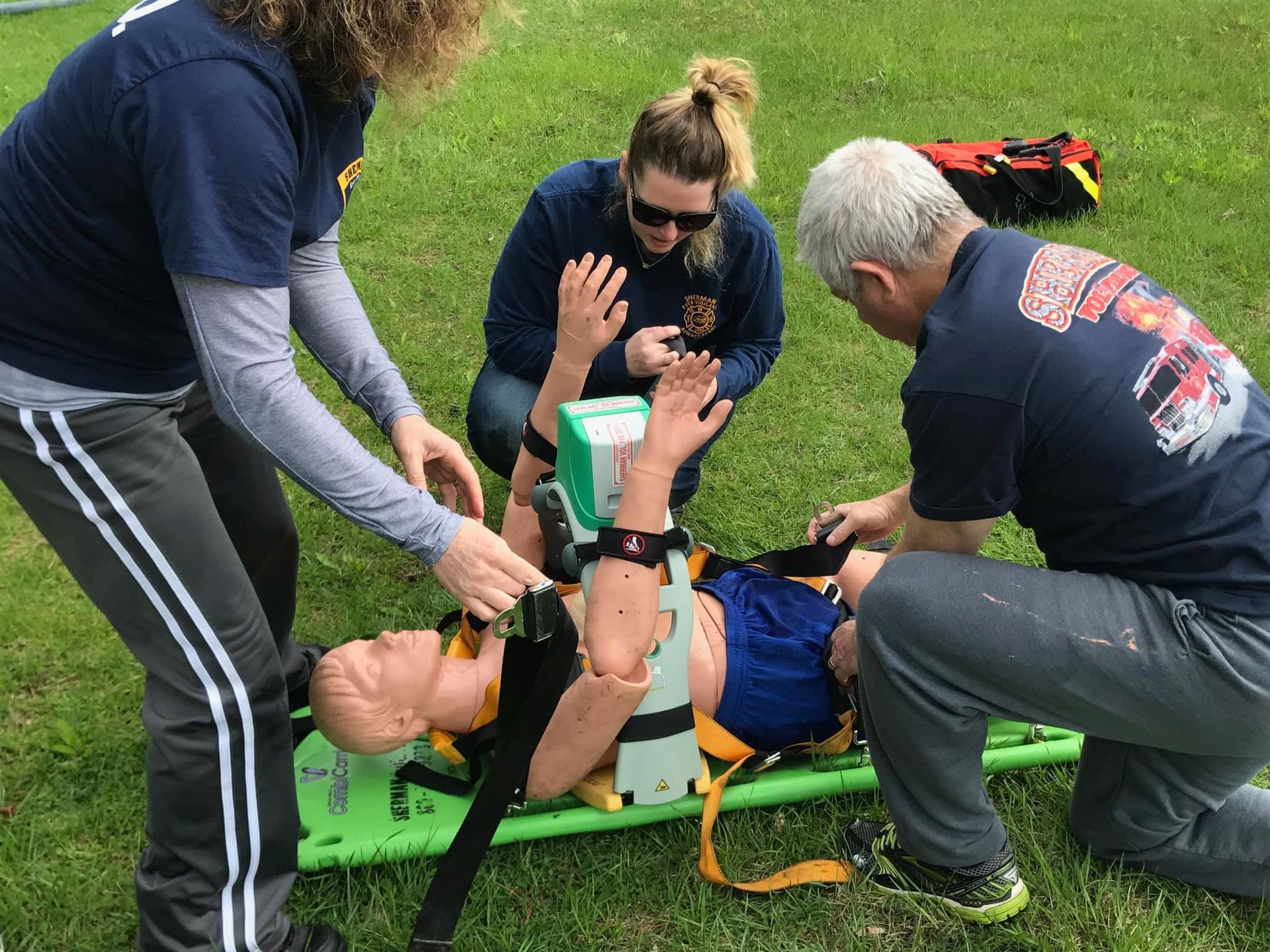 A group of people are kneeling around a mannequin on a stretcher.