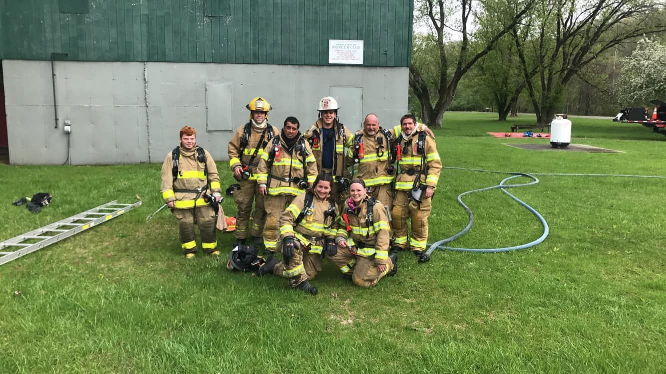 A group of firefighters are posing for a picture in a grassy field.