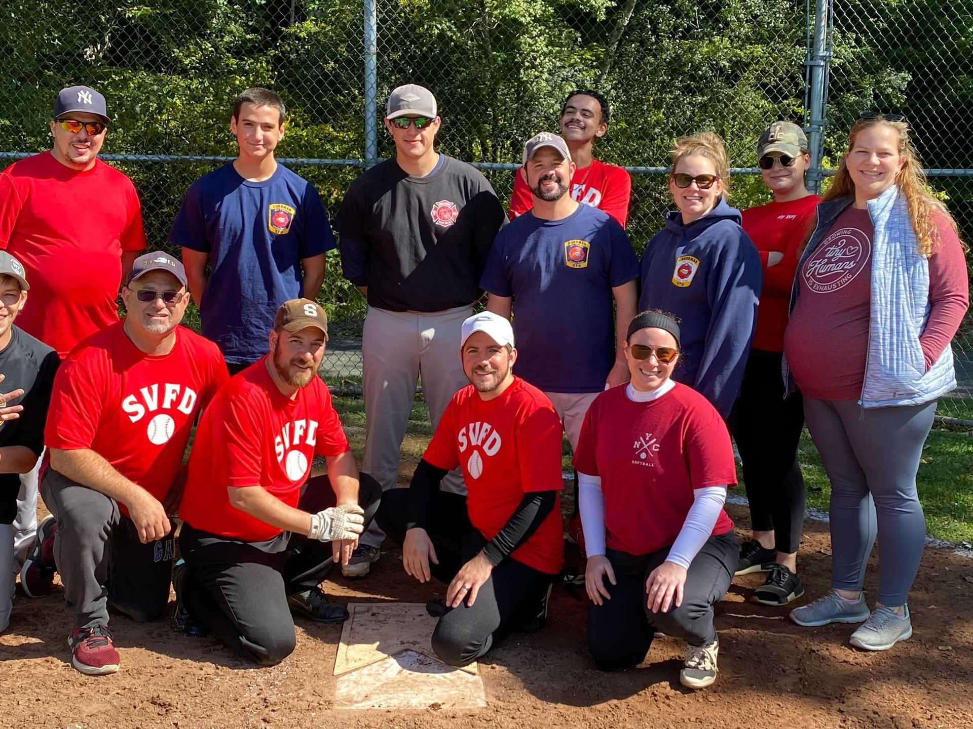 A group of people are posing for a picture on a baseball field.