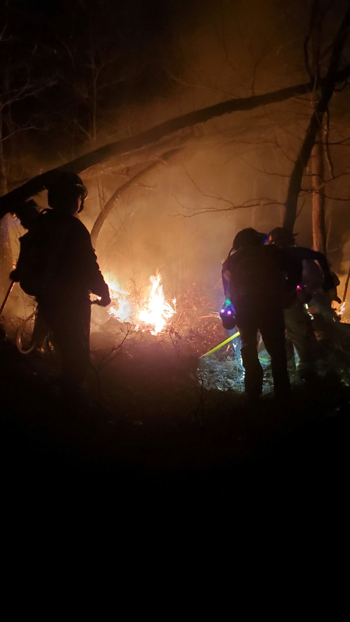 A group of firefighters are standing in front of a large fire.