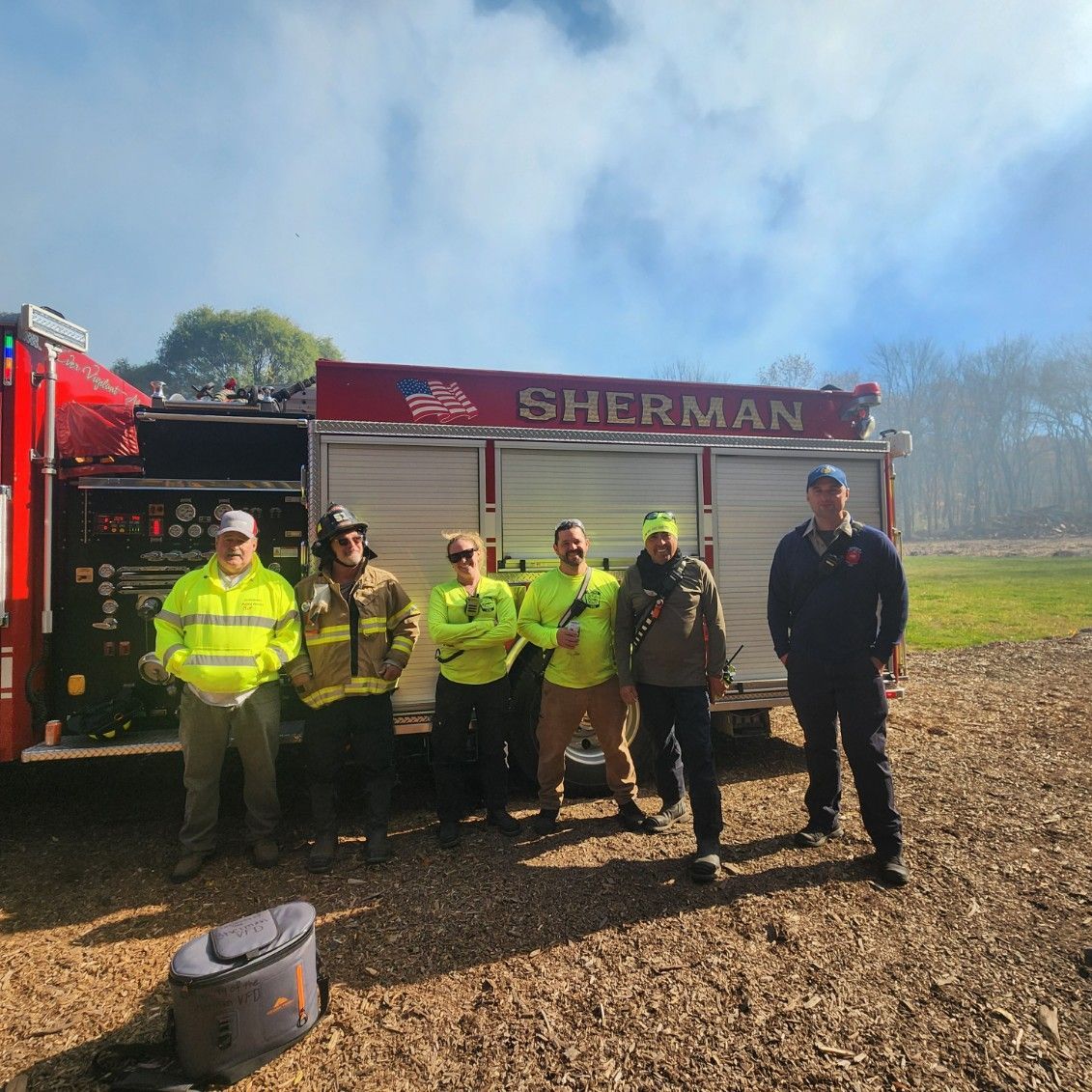 A group of firefighters standing in front of a sherman fire truck
