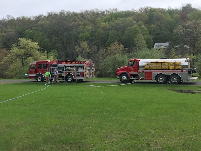 Two fire trucks are parked in a grassy field.
