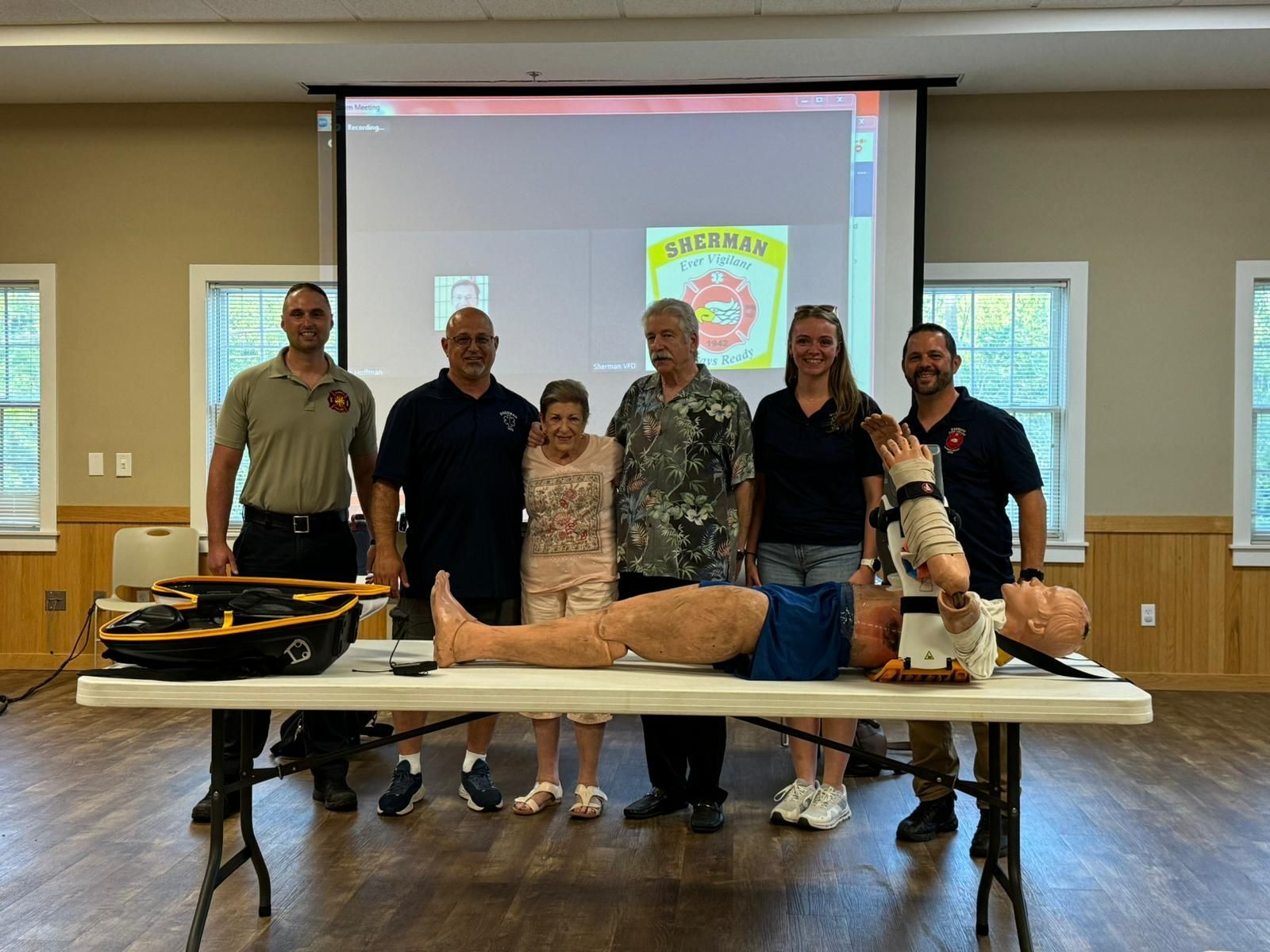 A group of people standing around a table with a mannequin on it.