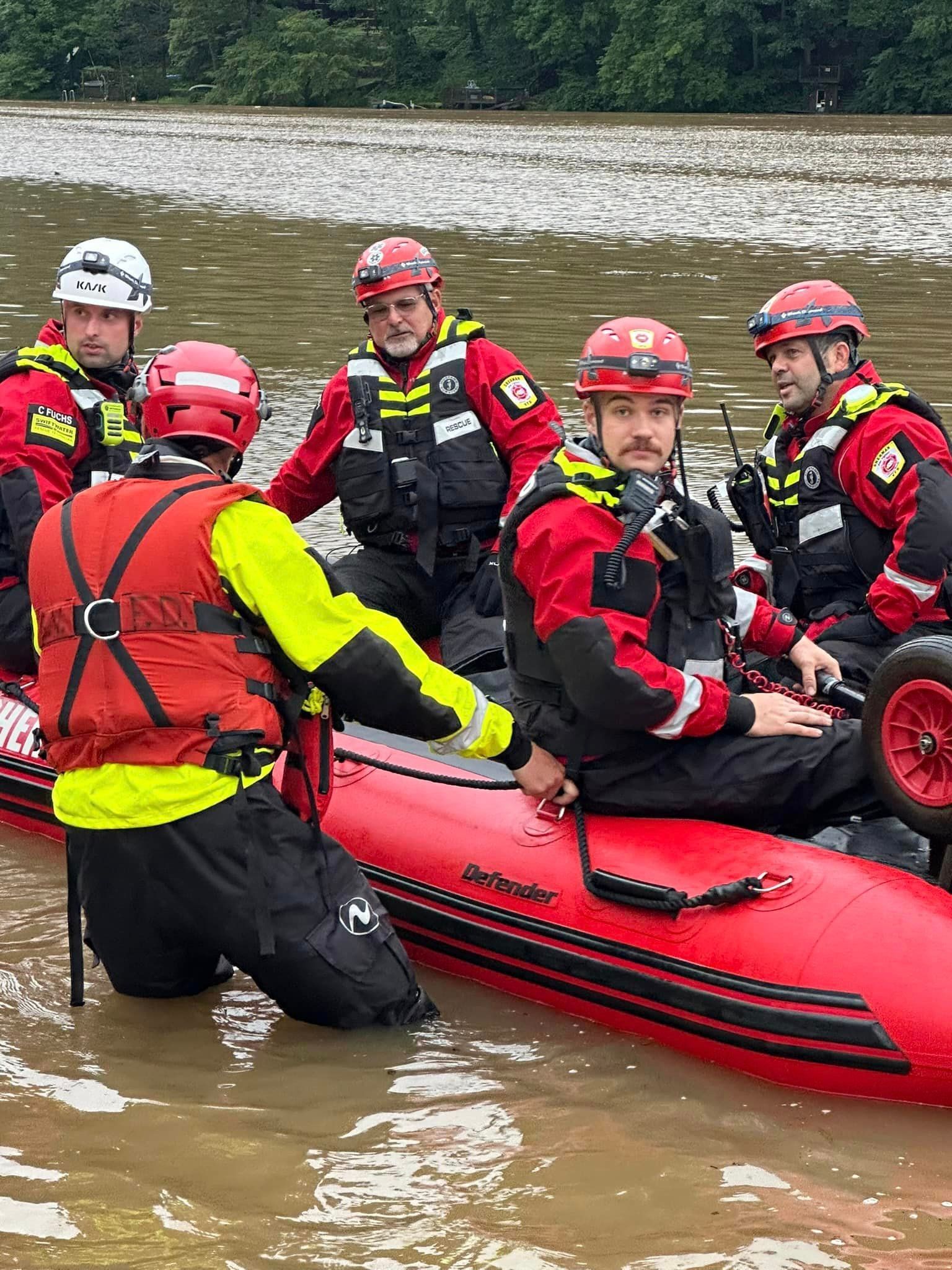 A group of men are sitting on top of a red raft in the water.
