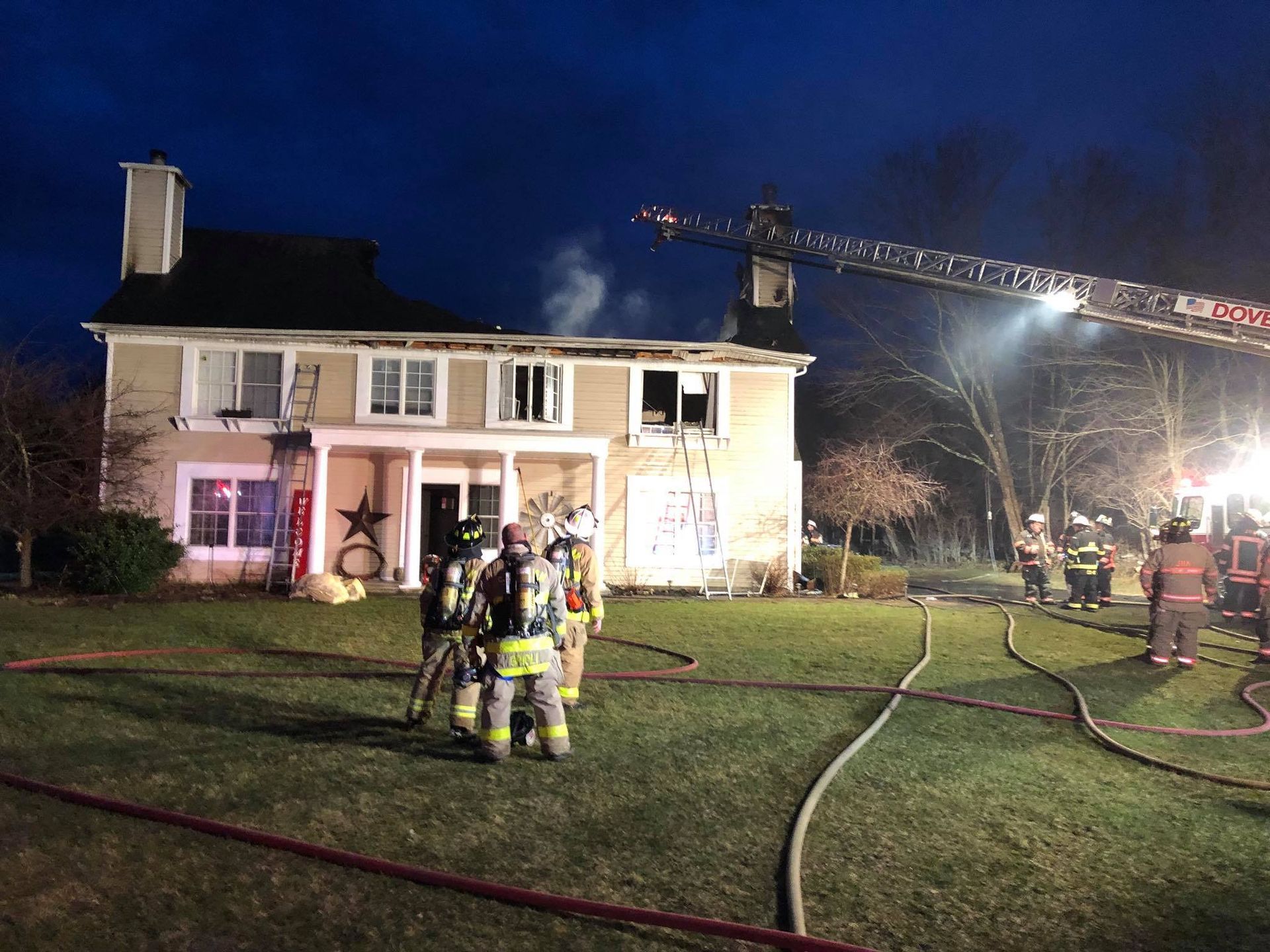 A group of firefighters are standing in front of a house.