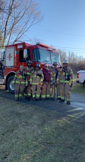 A group of firefighters are posing for a picture in front of a fire truck.