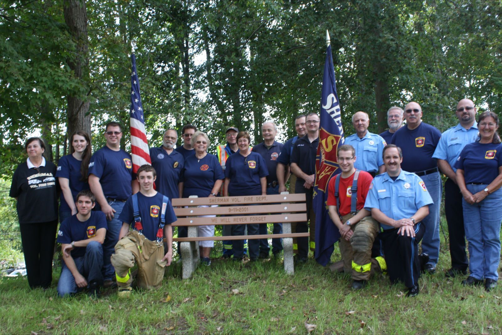 A group of firefighters are posing for a picture in front of a wooden bench