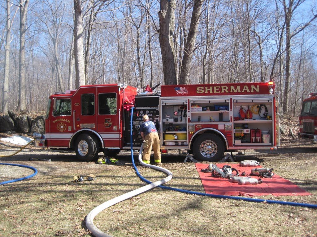 A sherman fire truck is parked in a field