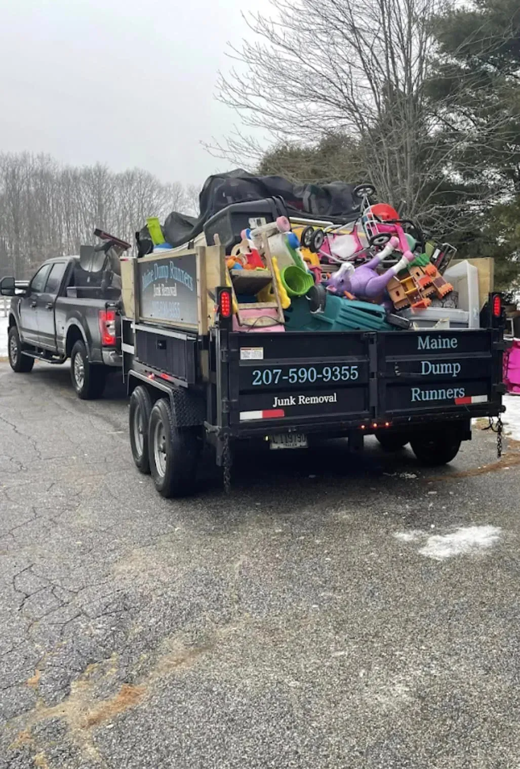 A dump truck filled with lots of junk is parked on the side of the road.