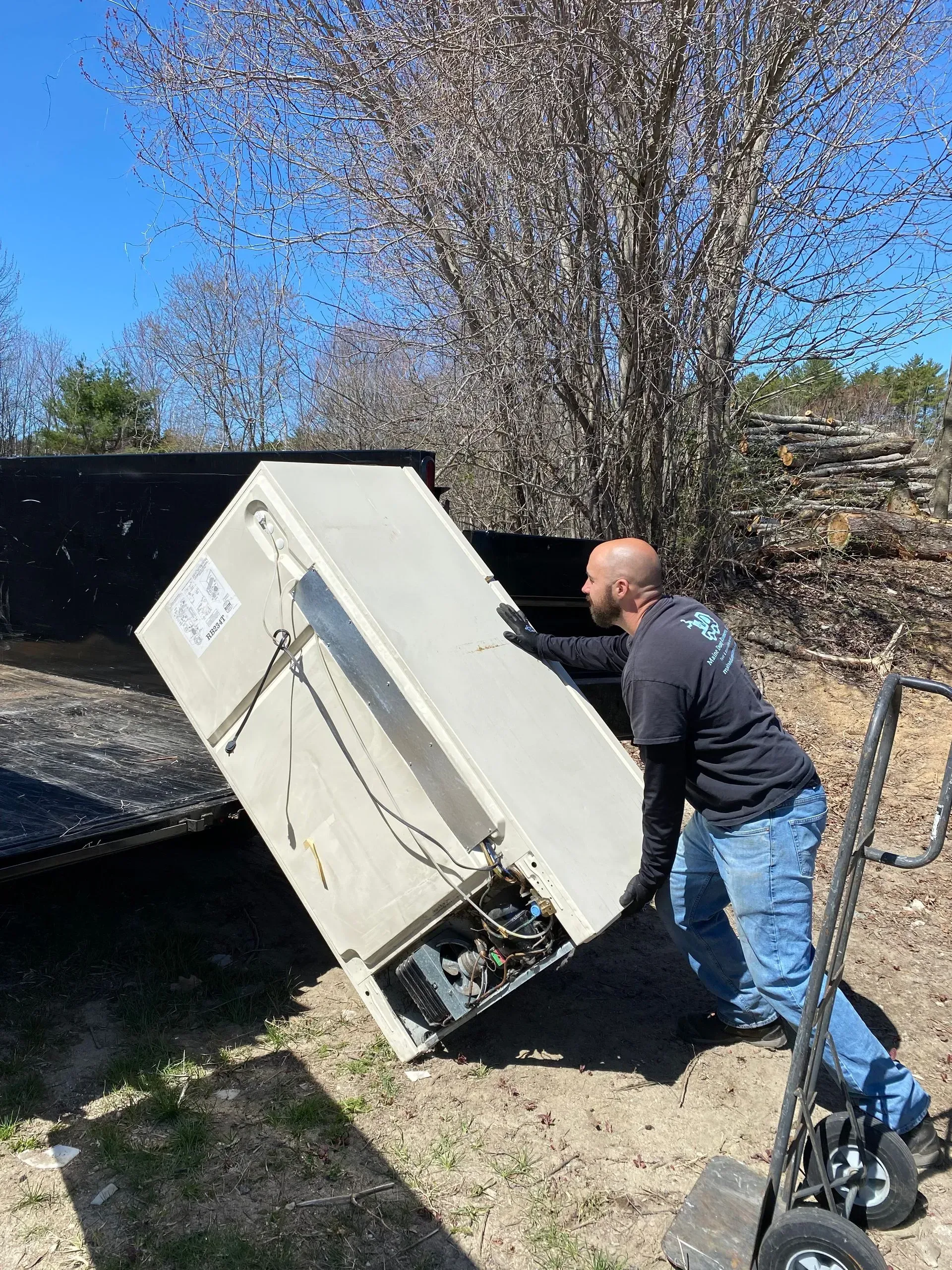 A man is lifting a refrigerator out of a truck.