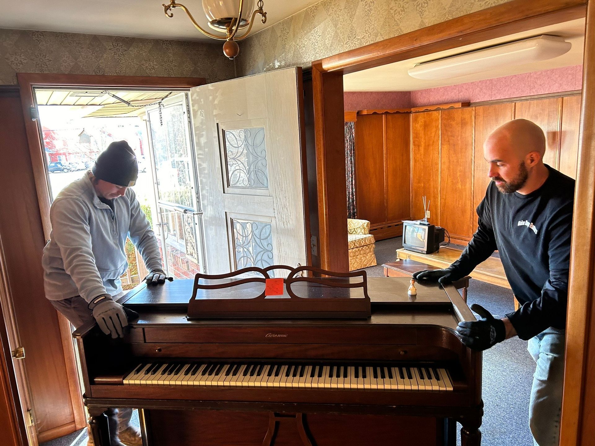 Two men are moving a piano into a room.