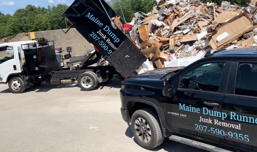 A dump truck and a car are parked next to a pile of junk.