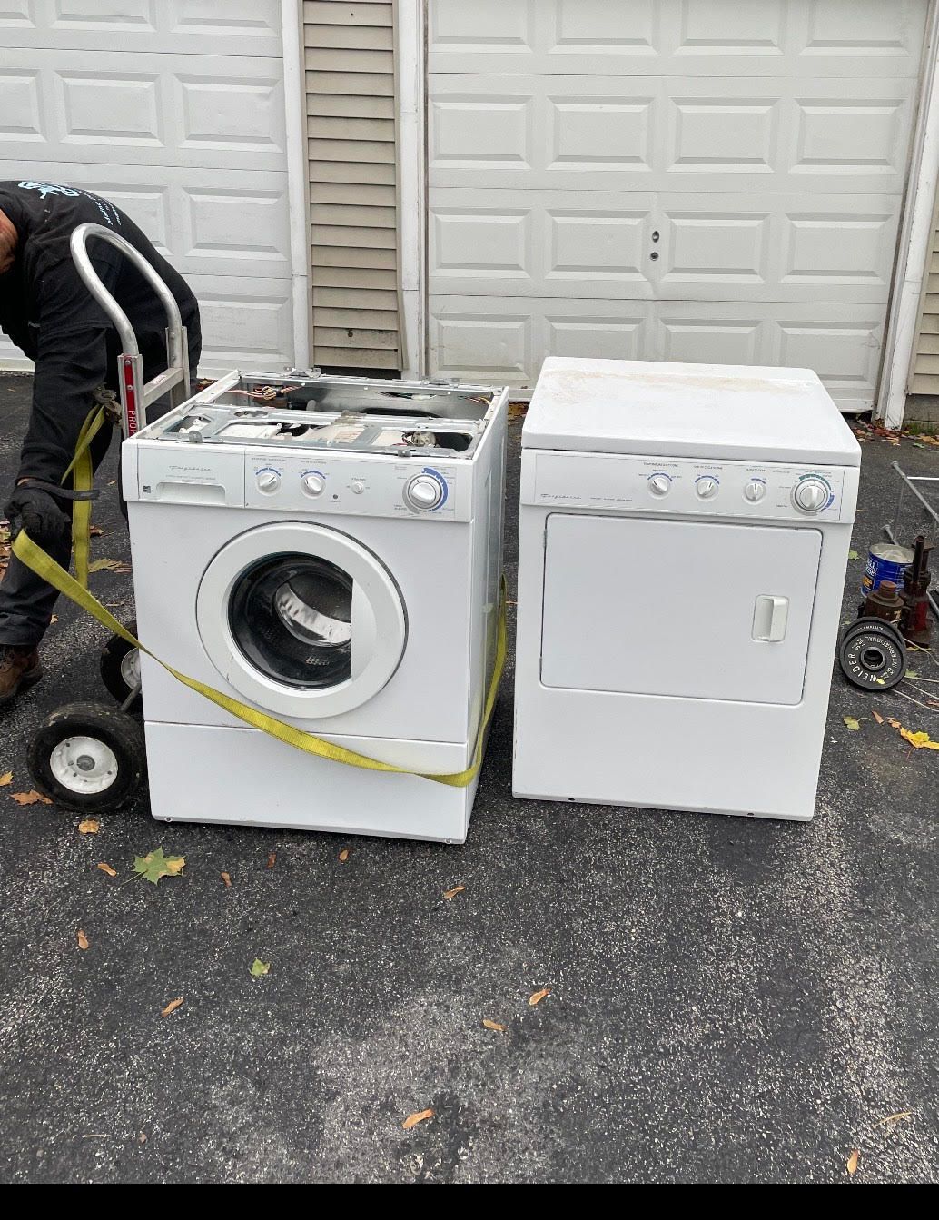 A washer and dryer are sitting next to each other in a driveway.